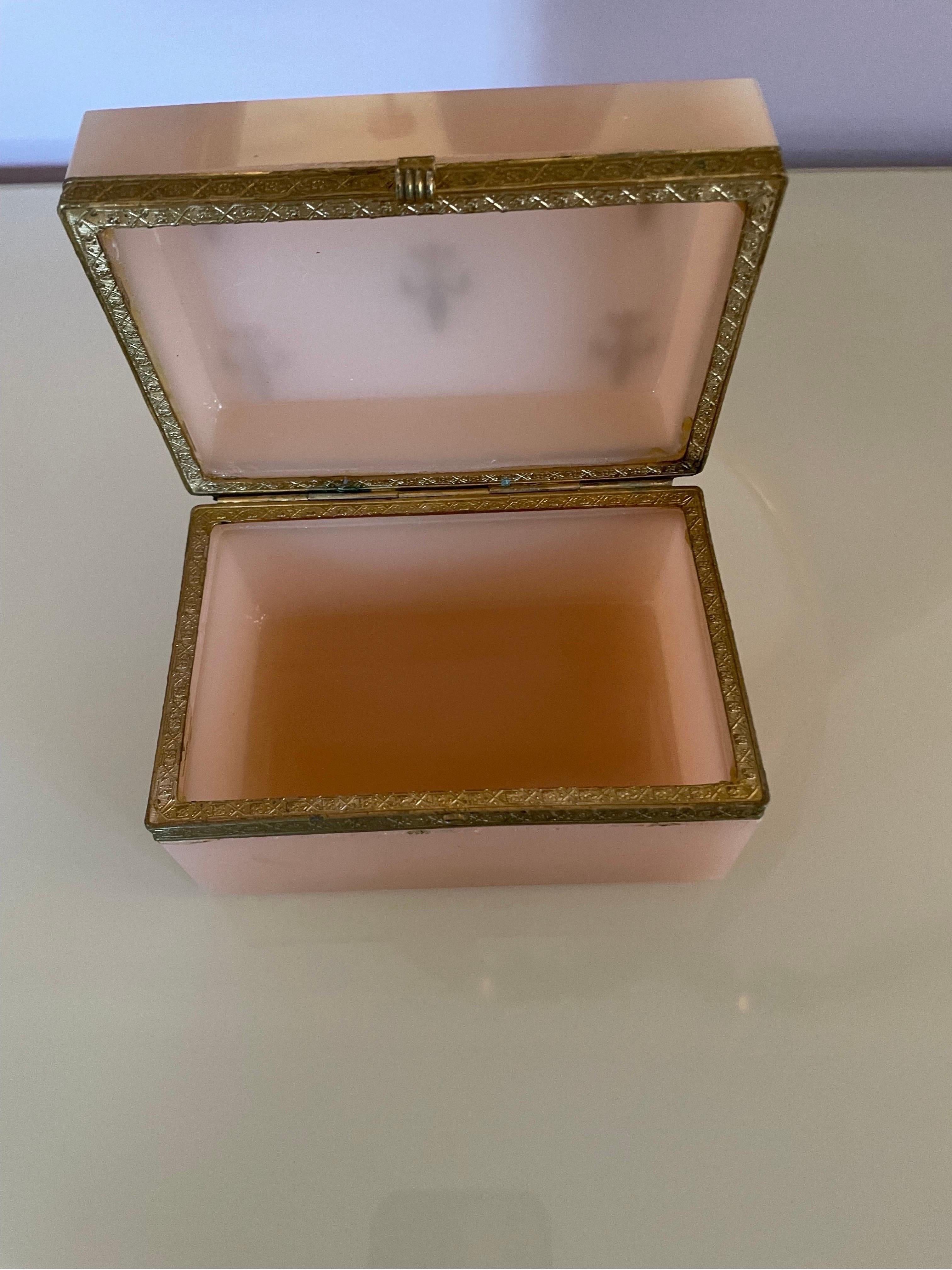 This is a heavy vintage opaline box probably from the 1950s 
It is a pale pink color with gold fleurdelis on top 
It has no cracks or chips and has gold ormolou around the box.