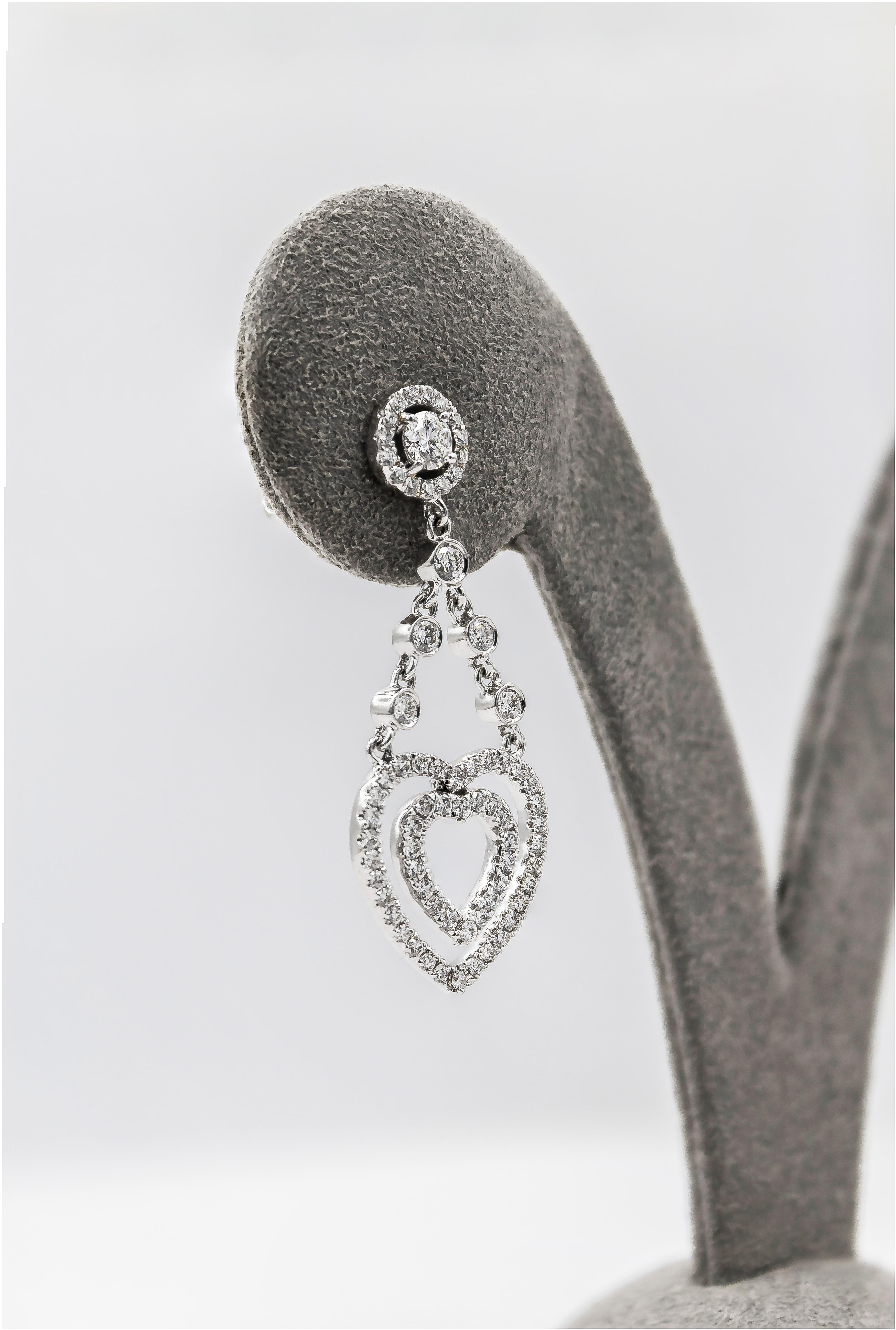 Stylish pair of open-work design dangle earrings showcasing brilliant round diamonds set in a double heart design, Suspended on a diamonds by the yard chain and a diamond encrusted post. Diamonds weigh 1.12 carats total. Made in 18K White Gold.