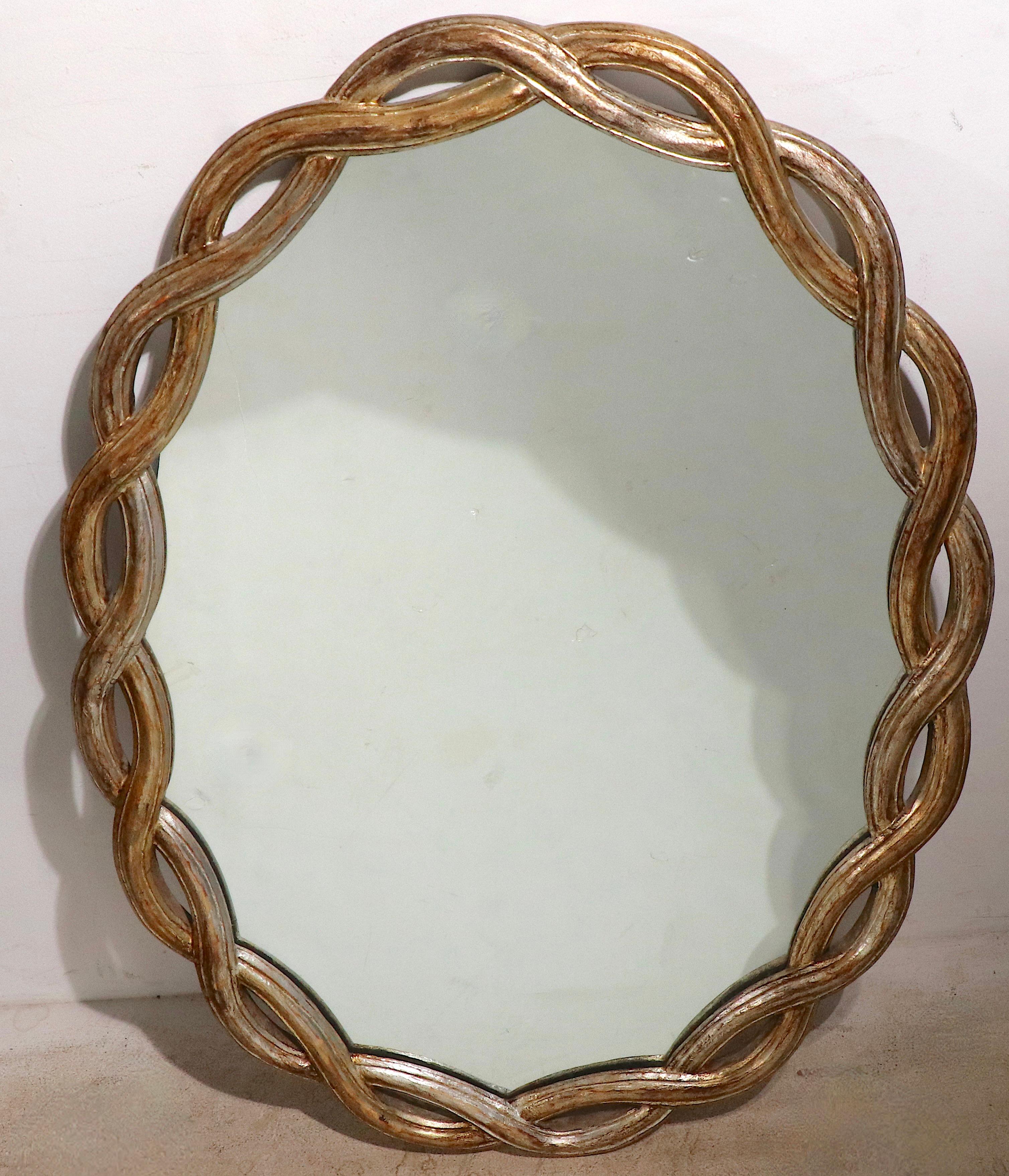 Super chic silver gilt mirror of hand carved wood and glass. The mirror features an open work weave pattern frame, which surrounds the bright and clean mirror center. This example is in very good, clean, original, ready to hang condition, showing