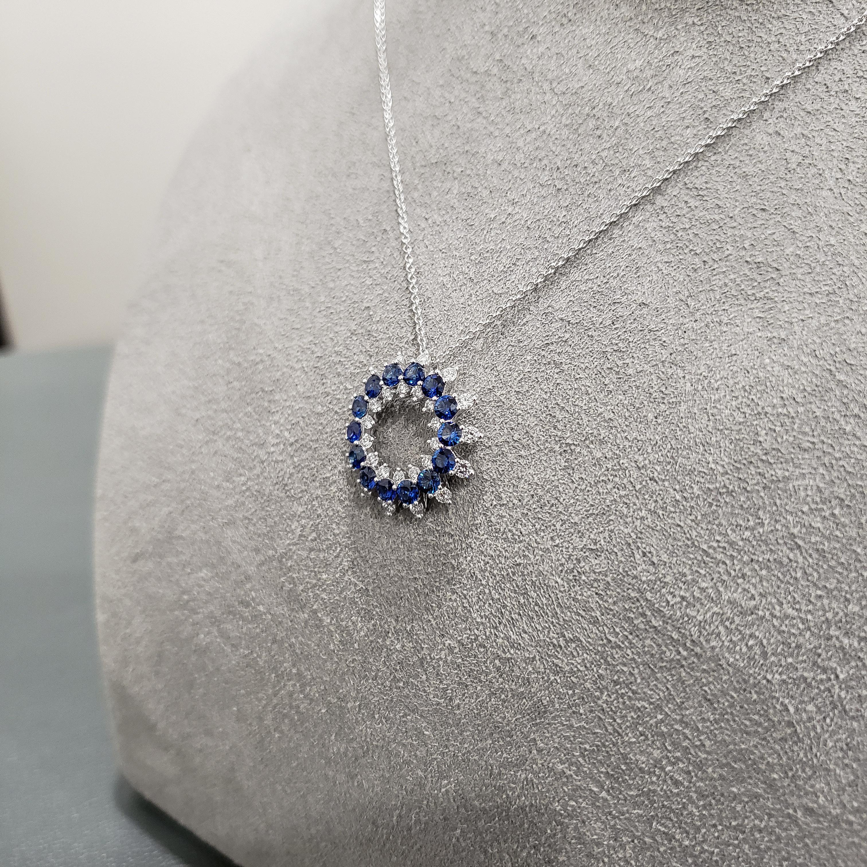 A very fashionable pendant necklace showcasing blue sapphires arranged in an open-work circular design accented with round brilliant diamonds. Sapphires weigh 1.52 carats total; diamonds weigh 0.59 carats total. Made in 18 karat white gold. 

