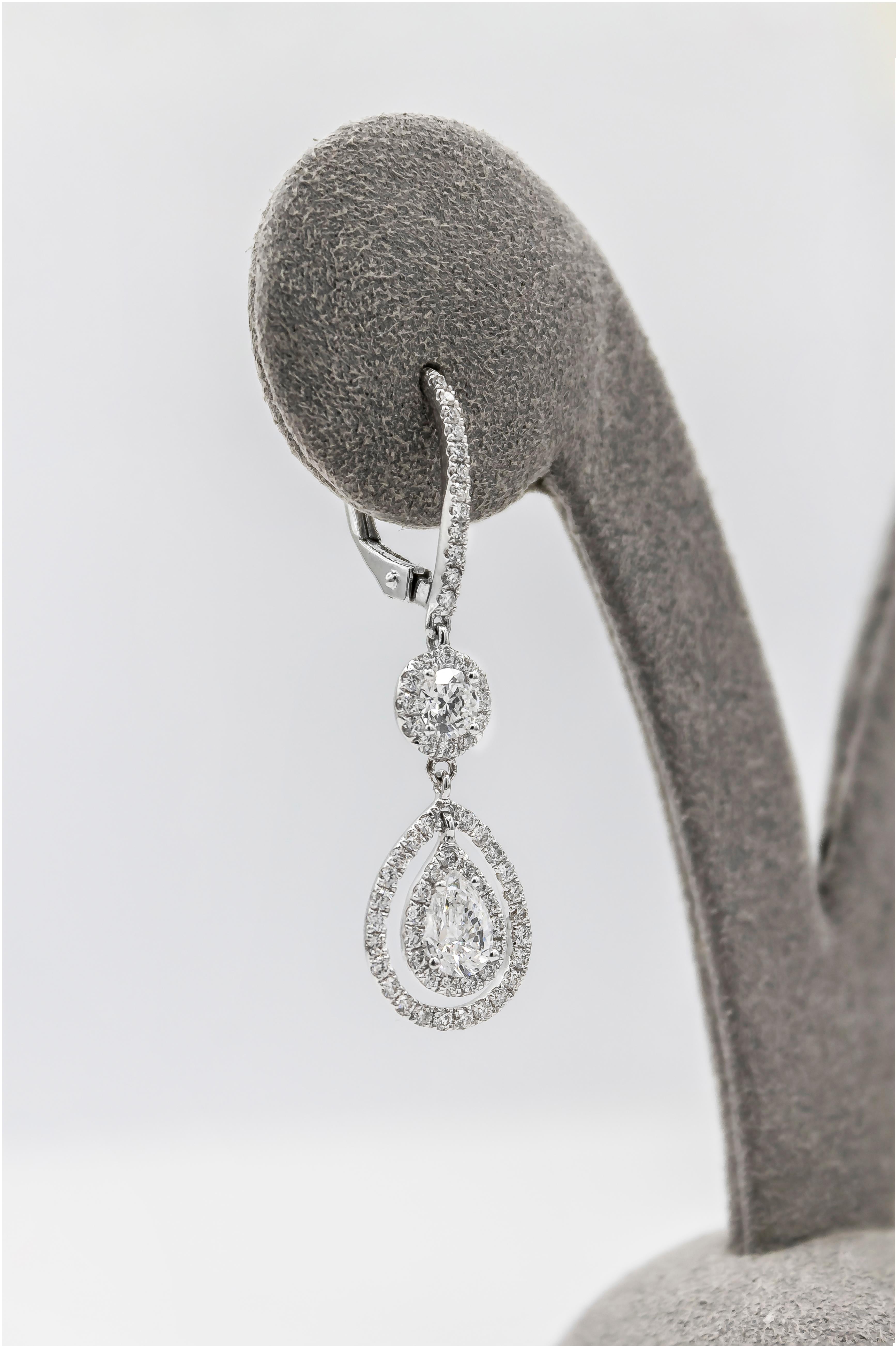 A brilliant pair of earrings showcasing a pear shape diamond weighing 0.63 carats in the center, surrounded by two rows of brilliant round diamonds in a halo design, and suspended on a diamond encrusted hoop. Made in 18K White Gold. 

Style