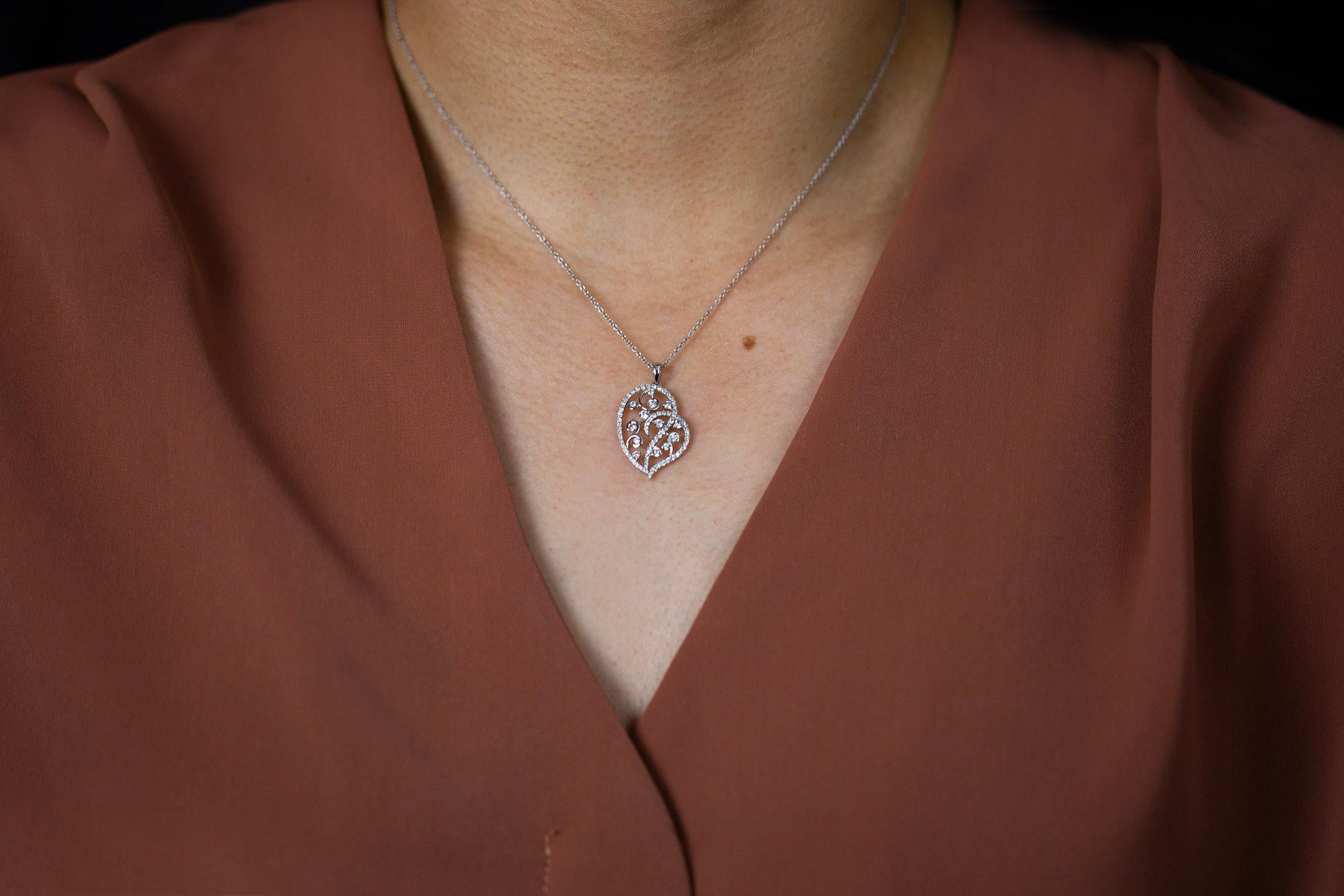 This fashionable pendant necklace features an intricate open-work heart shape design set with diamonds for that added sparkle. Diamonds weigh 0.69 carats total. Finely made in 18k white gold composition and suspended on an 18 inches adjustable