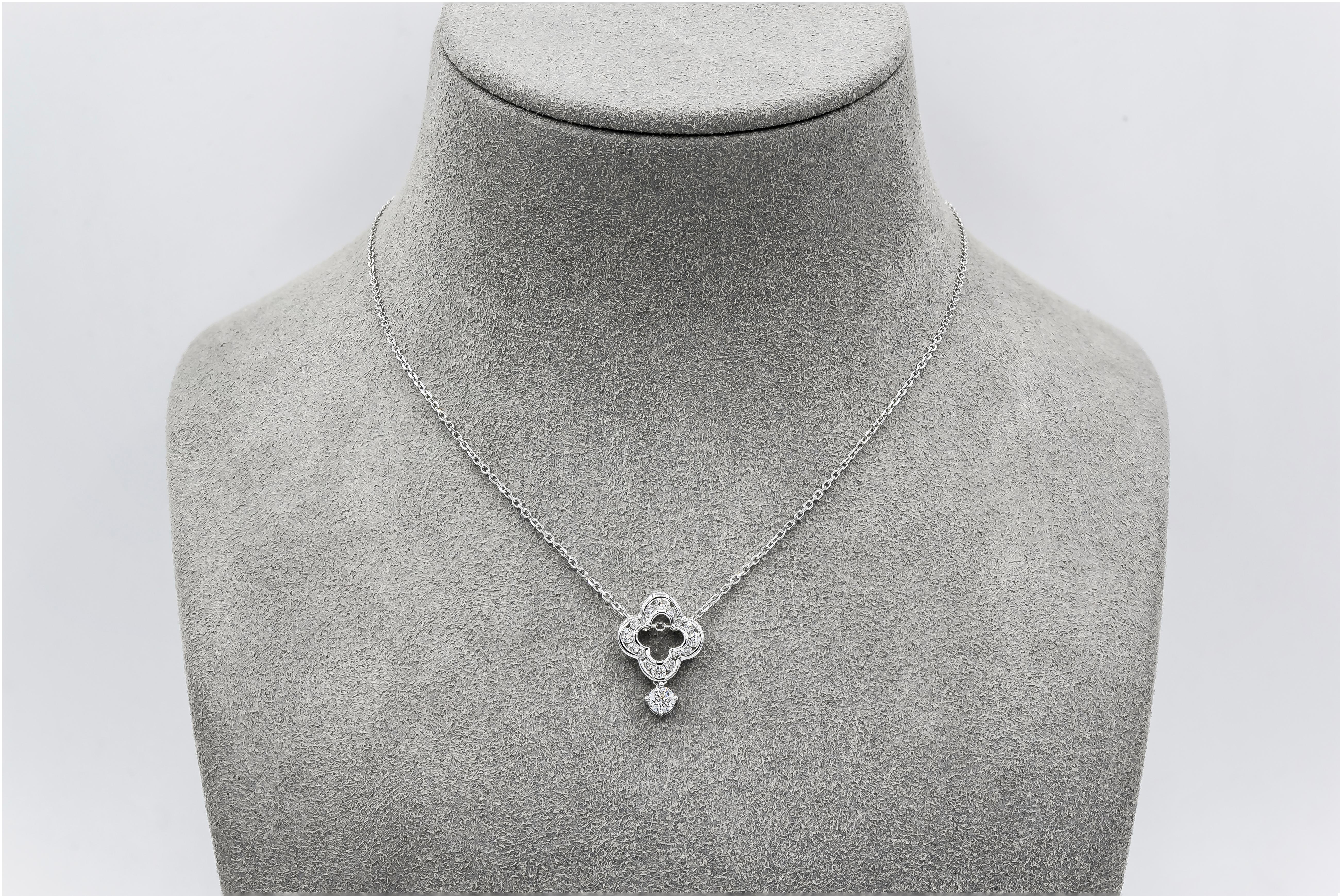 A stylish pendant necklace showcasing an open-work four point clover design, channel set with round brilliant diamonds weighing 0.35 carats total. Dangling the open-work design is a single round diamond weighing 0.22 carats total. Suspended on an 18