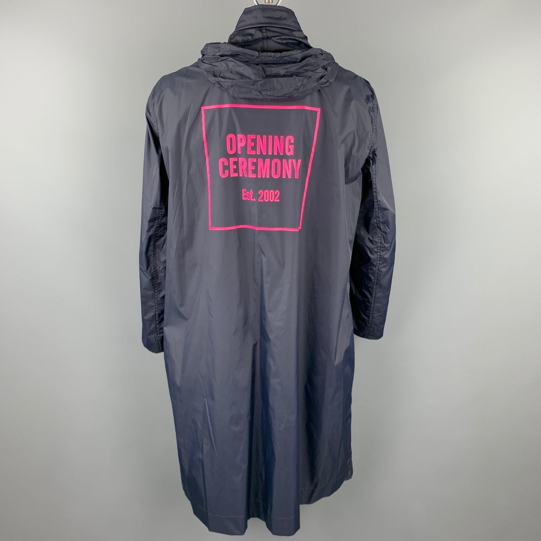 OPENING CEREMONY rain coat comes in a navy nylon featuring a hidden hood style, back logo design, front pockets, and a buttoned closure.
New With Tags. 

Marked:  L 

Measurements: 
 
Shoulder: 22 inches 
Chest: 50 inches 
Sleeve: 27 inches 
Length: