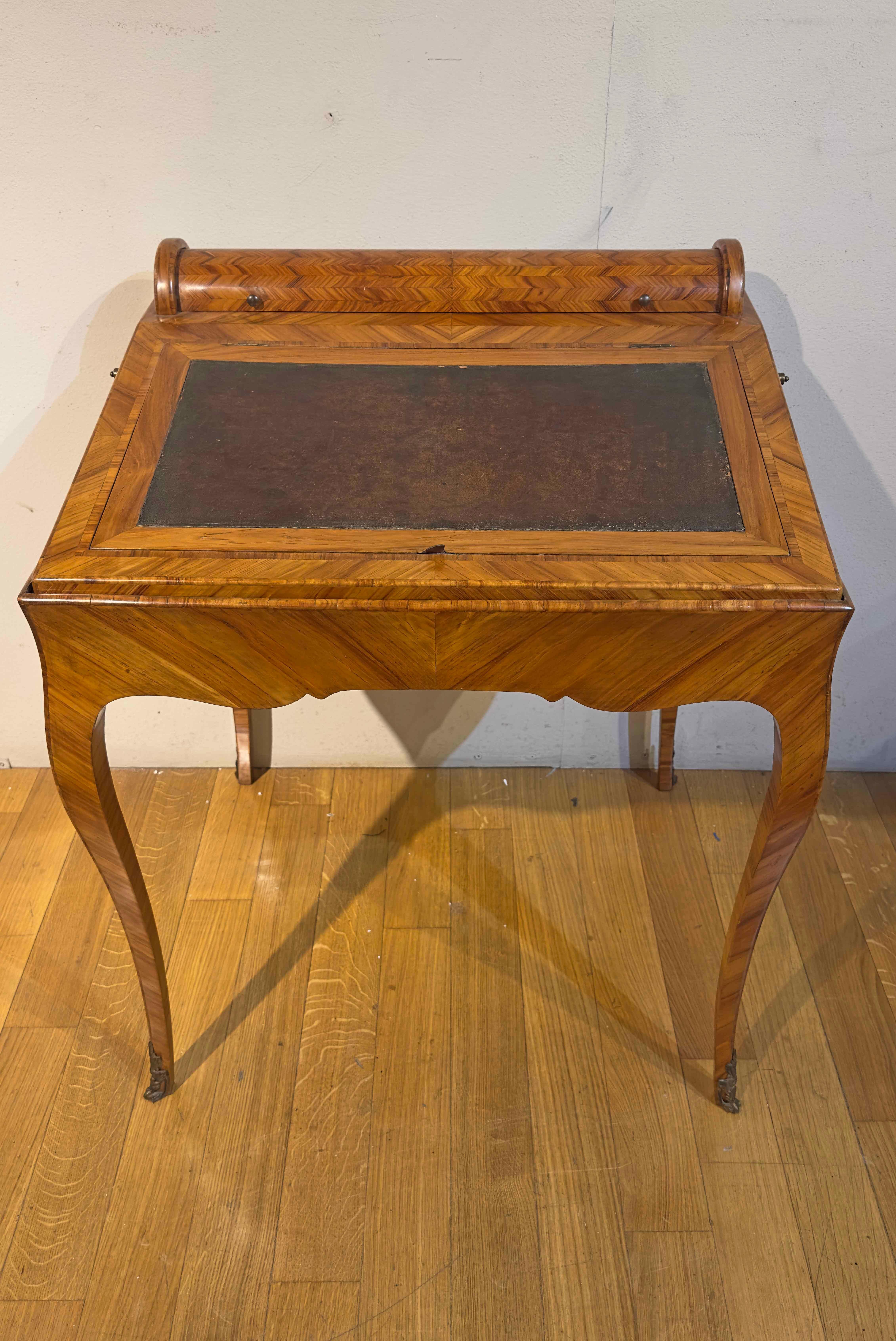 Elegantes Schreibpult für die Mitte, vollständig mit Obstholz furniert. Dieses raffinierte Möbelstück zeichnet sich durch seine gewölbte Bande und die leicht geschwungenen Beine aus, die durch mit Bronzedetails verzierte Füße bereichert werden, die