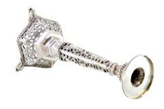 Openwork silver candlestick with hexagonal base and carved obelisk wall light