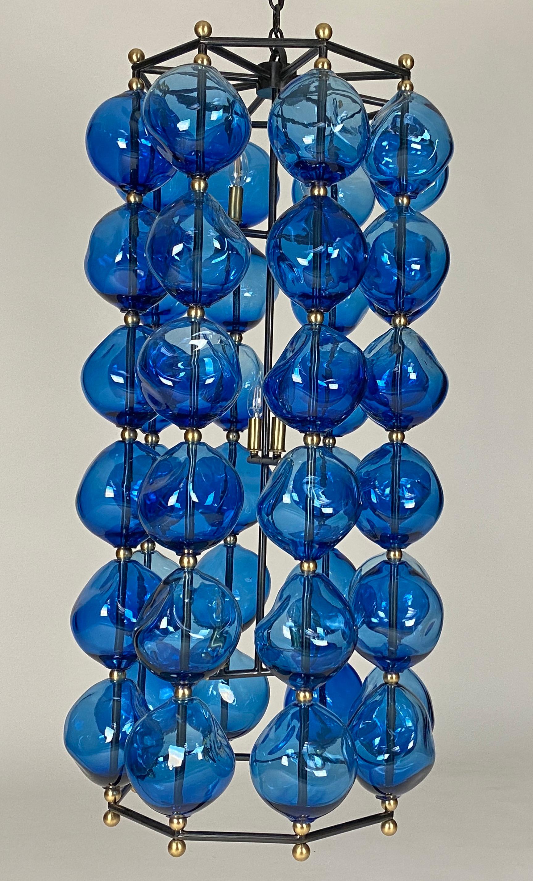 Steel and hand blown glass chandelier. 48 aqua blue glass stones. Gun metal steel frame and brass accents. 4 candelabras base sockets
Custom sizes available