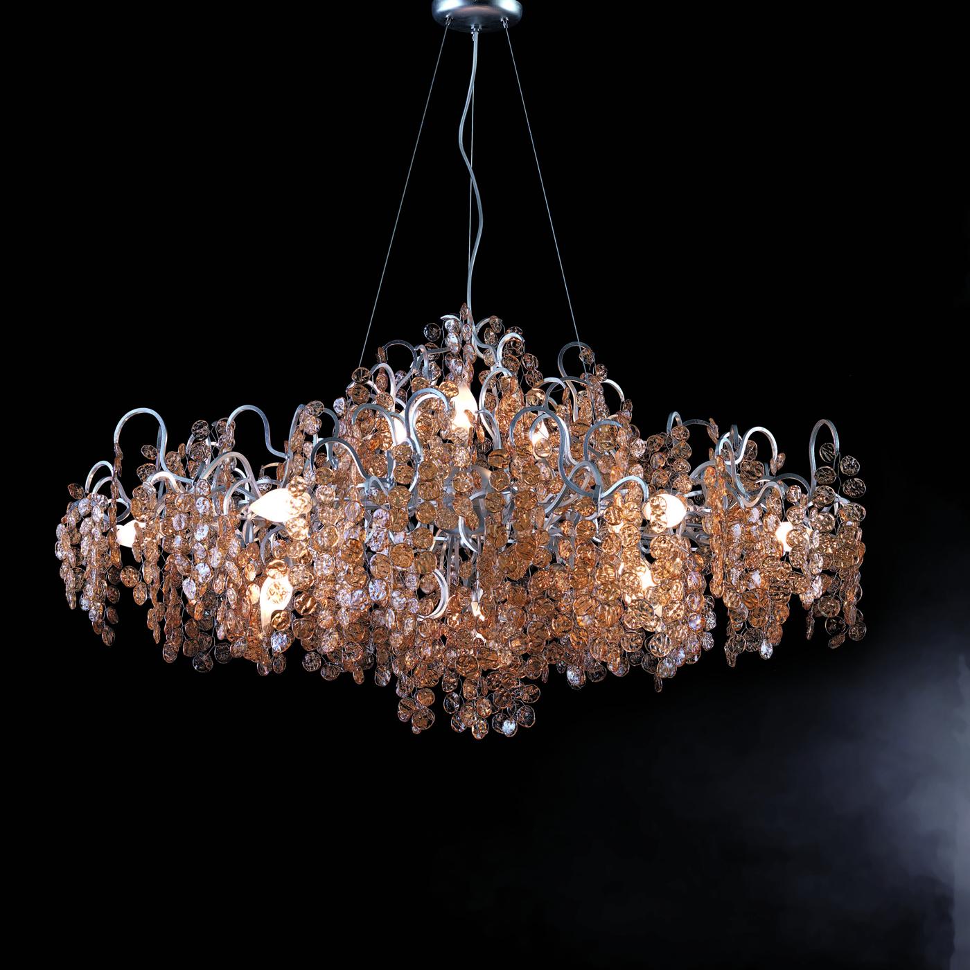 Exuding a resplendent allure thanks to the minute craftsmanship featured in its creation, this exquisite chandelier boasts a sinuous metal frame covered with silver leaf. The 12 ES bulbs (G9 and max. 33W each) spread an intense light that sublimely