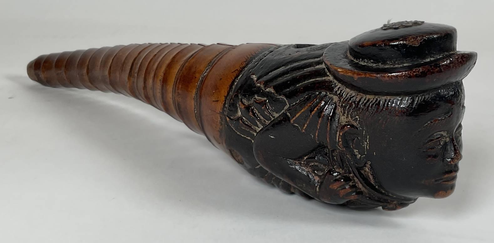 Intricately carved opium pipe from the nineteenth century. Womans head is neatly carved showing arms, hands, hat, etc.. Great patina. One split on top. Metal rosette affixed to the top of the hat. Quite a rare piece. 14