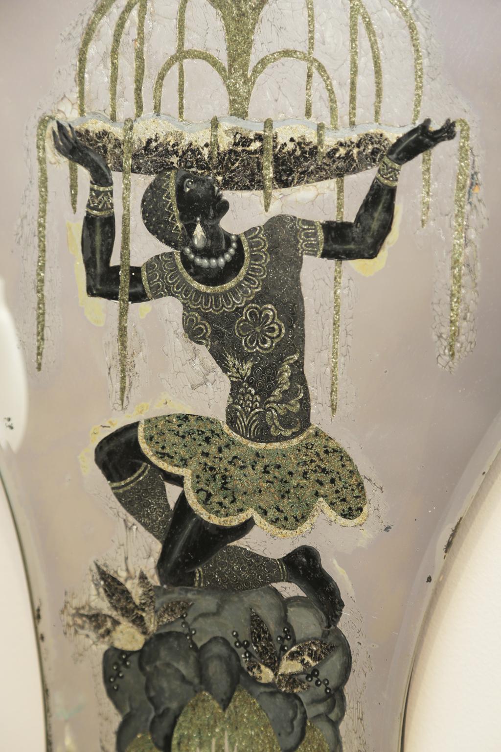 A right and left pair of sconces, each having a shield-shaped, mirrored backplate, reverse painted with Nubian figures, S-scroll candlearms, of brass, decorated with pendulum crystals. finished with palm accent below their electrified candles.