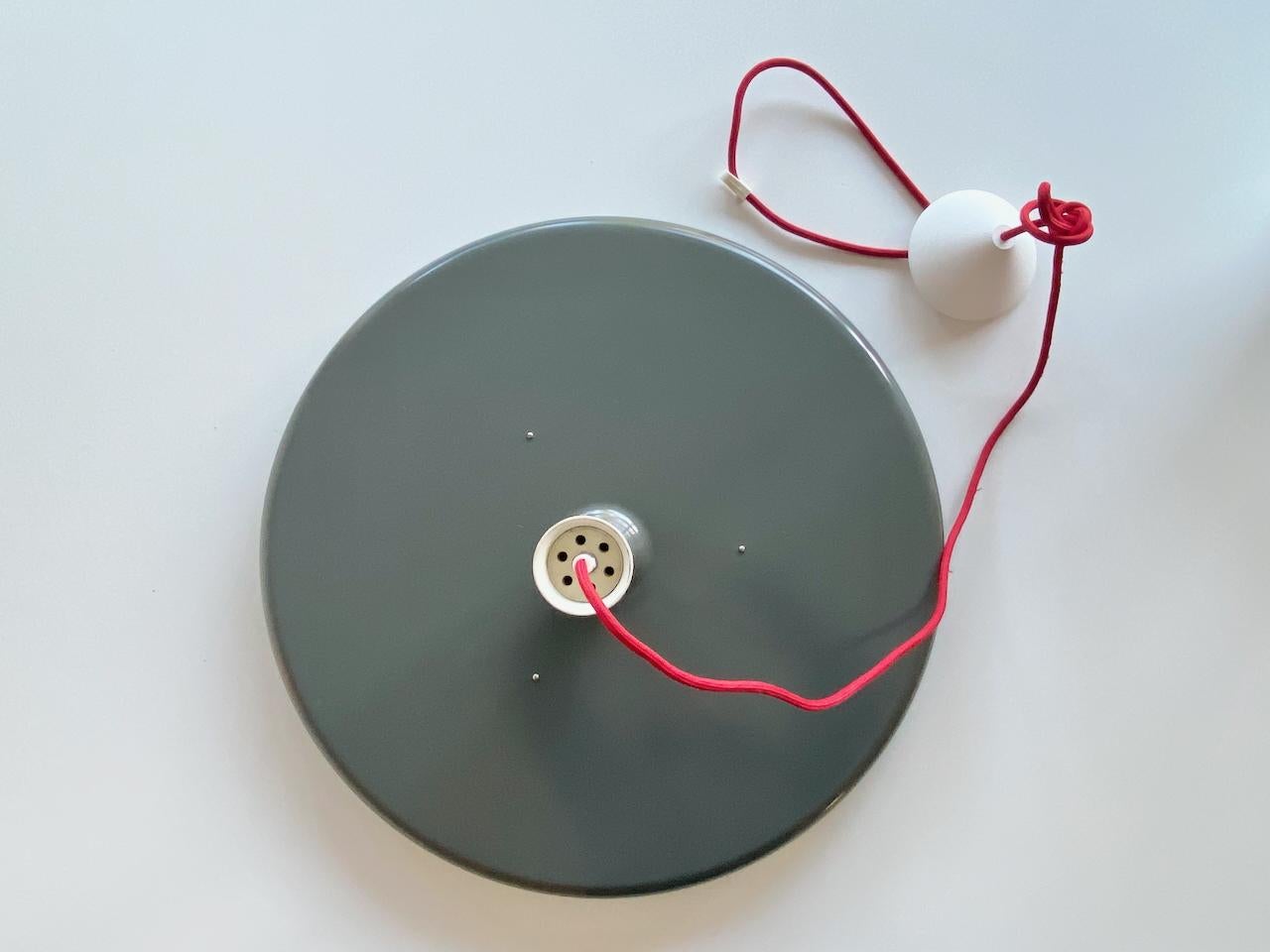 Bellissimo pendente Optima di colore grigio, bianco e rosso Design/One di Hans Due degli anni '70 e prodotto da Fog & Mørup Danimarca. 
L'interno dello schermo inferiore è di colore rosso che, quando la luce è accesa, emana un bellissimo effetto