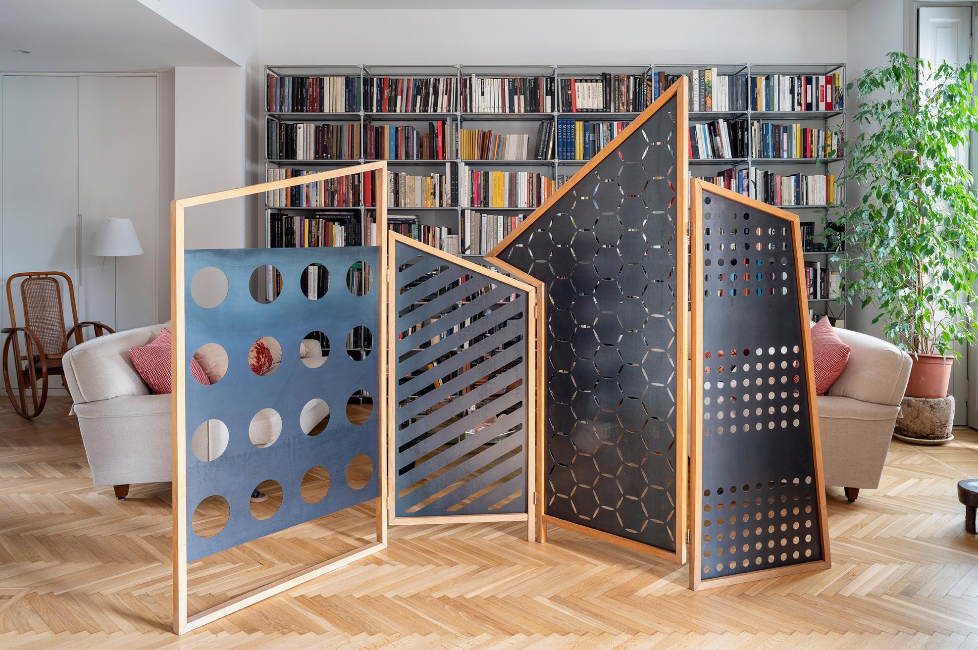 The structure of the folding screen is composed by four solid oak hand-made frames with an irregular geometry. Inside four contain black laser-cut steel panels.  
Its name is Opto, because clearly inspired by the patterns of the optical Bauhaus