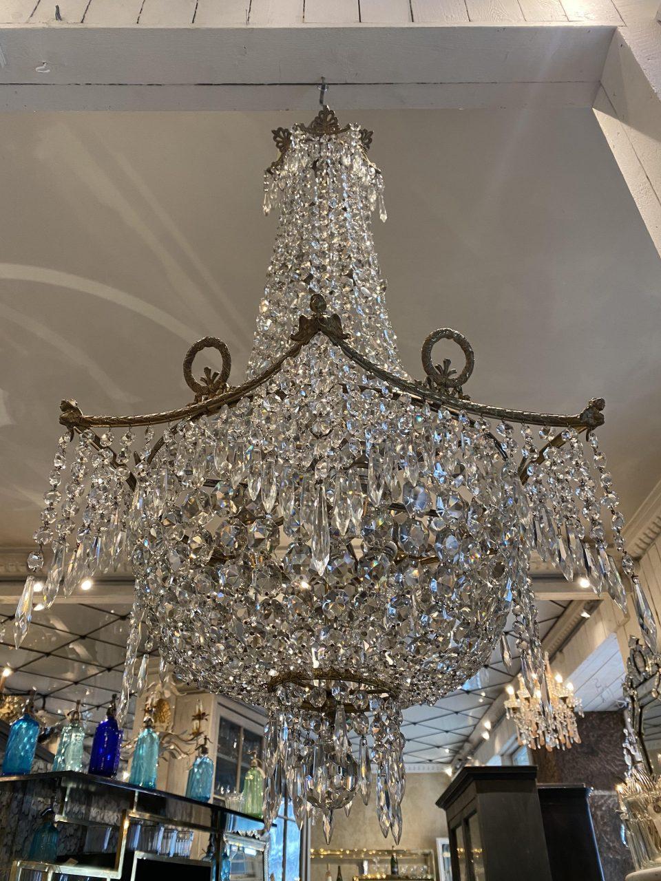 Absolutely beautiful antique stately crystal chandelier originating from France and the beginning of the last century.

Elegantly designed with a hexagonal brass band, on which sit 6 small victory wreaths with fine Louis XVI bows and 6 sphinx