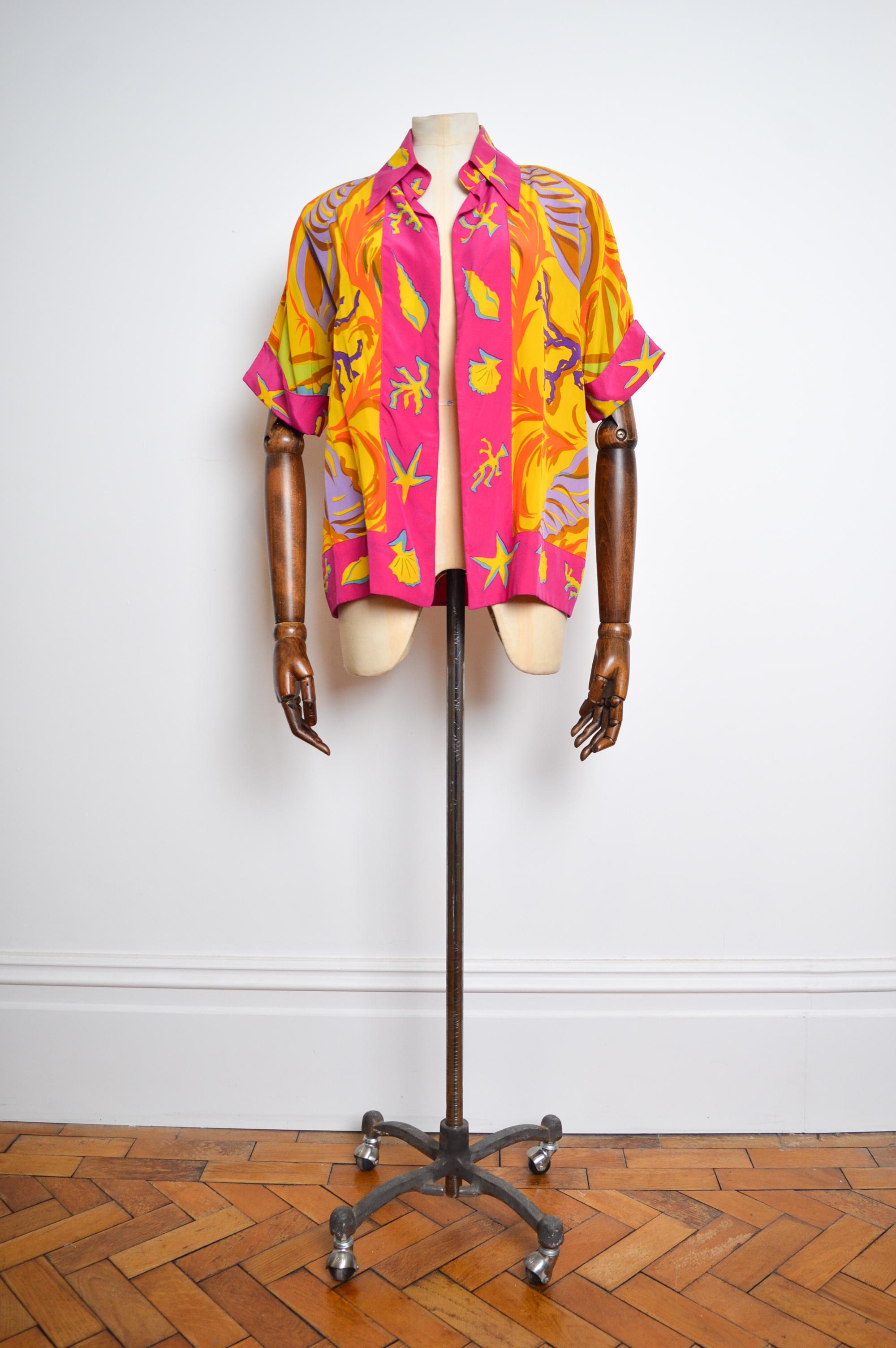 Opulenta chemise aperta in pura seta vintage degli anni '90 di Christian Lacroix, con una bellissima stampa astratta colorata. 

Questa camicia di grande effetto è caratterizzata da maniche corte, spalle padellate e vestibilità aperta sul