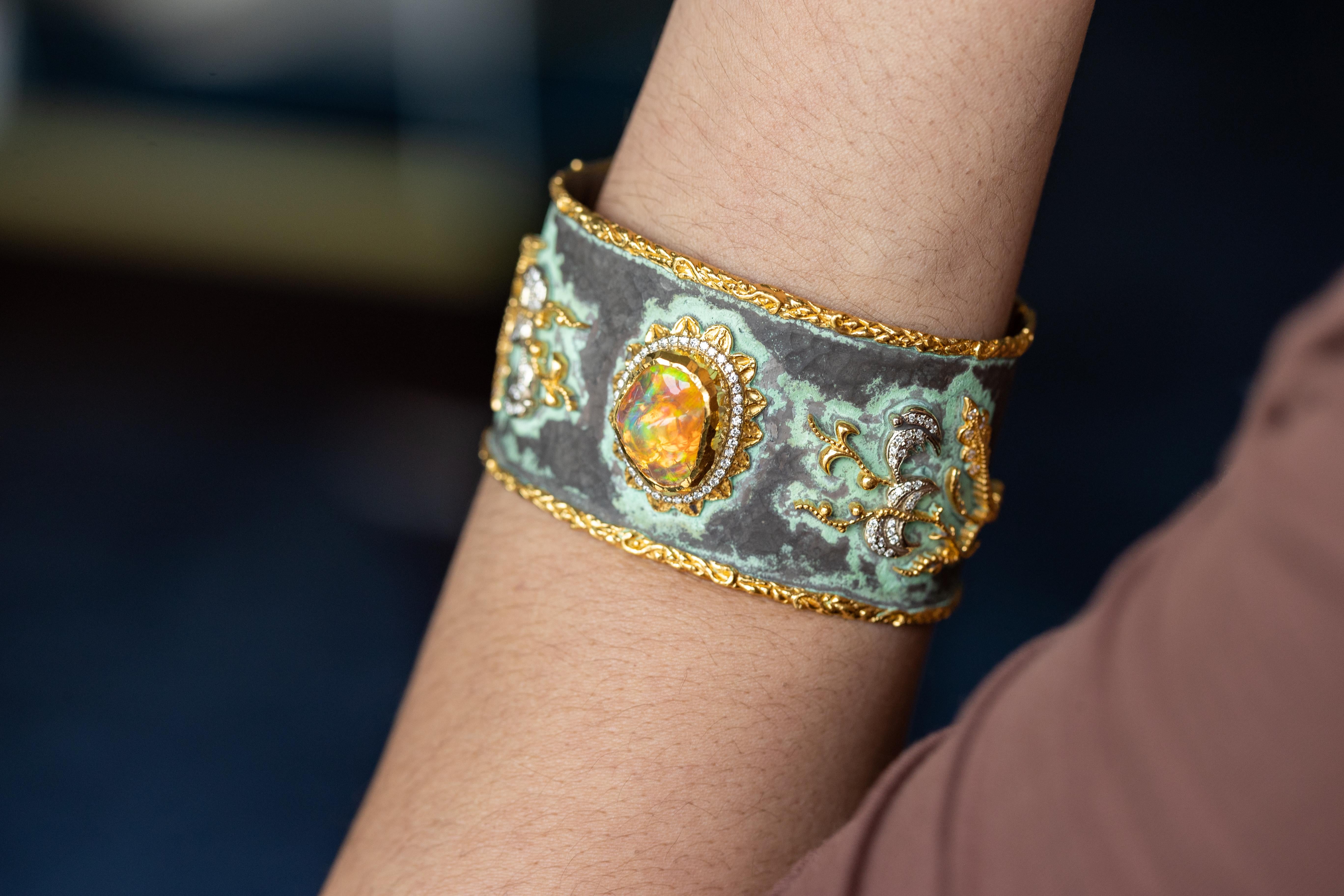 Step into a world of unparalleled elegance with this opulent cuff bracelet, a masterful creation by the esteemed designer Victor Velyan. Measuring 1.5 inches wide, this exquisite piece features a breathtaking 8.86-carat fire opal, renowned for its