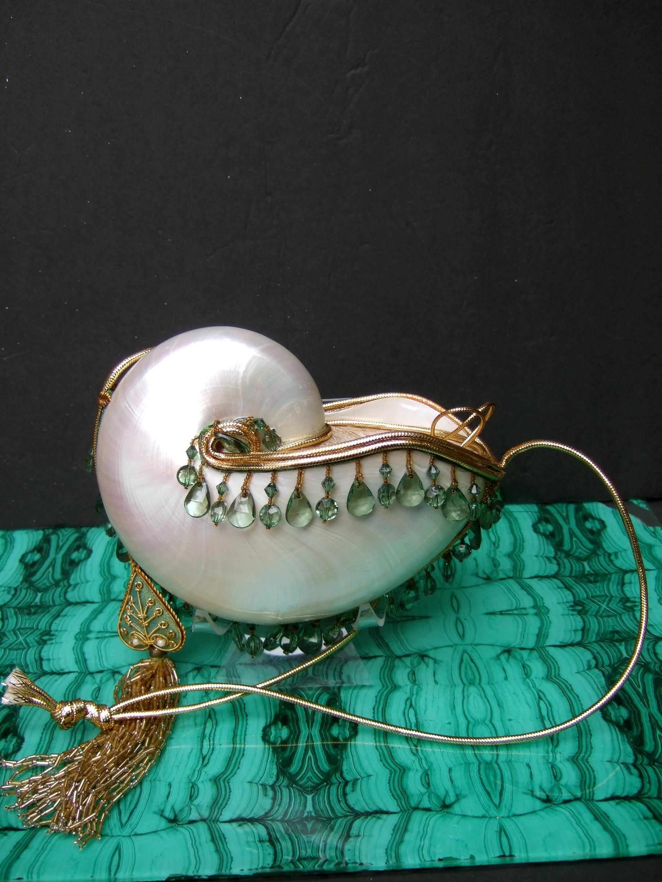 Opulent artisan chamber nautilus jeweled shell evening bag c 1970s
The elegant evening bag is designed with an organic large chamber nautilus sea shell
The shell has a luminous glowing patina

The exotic sea shell is embellished with gold metallic