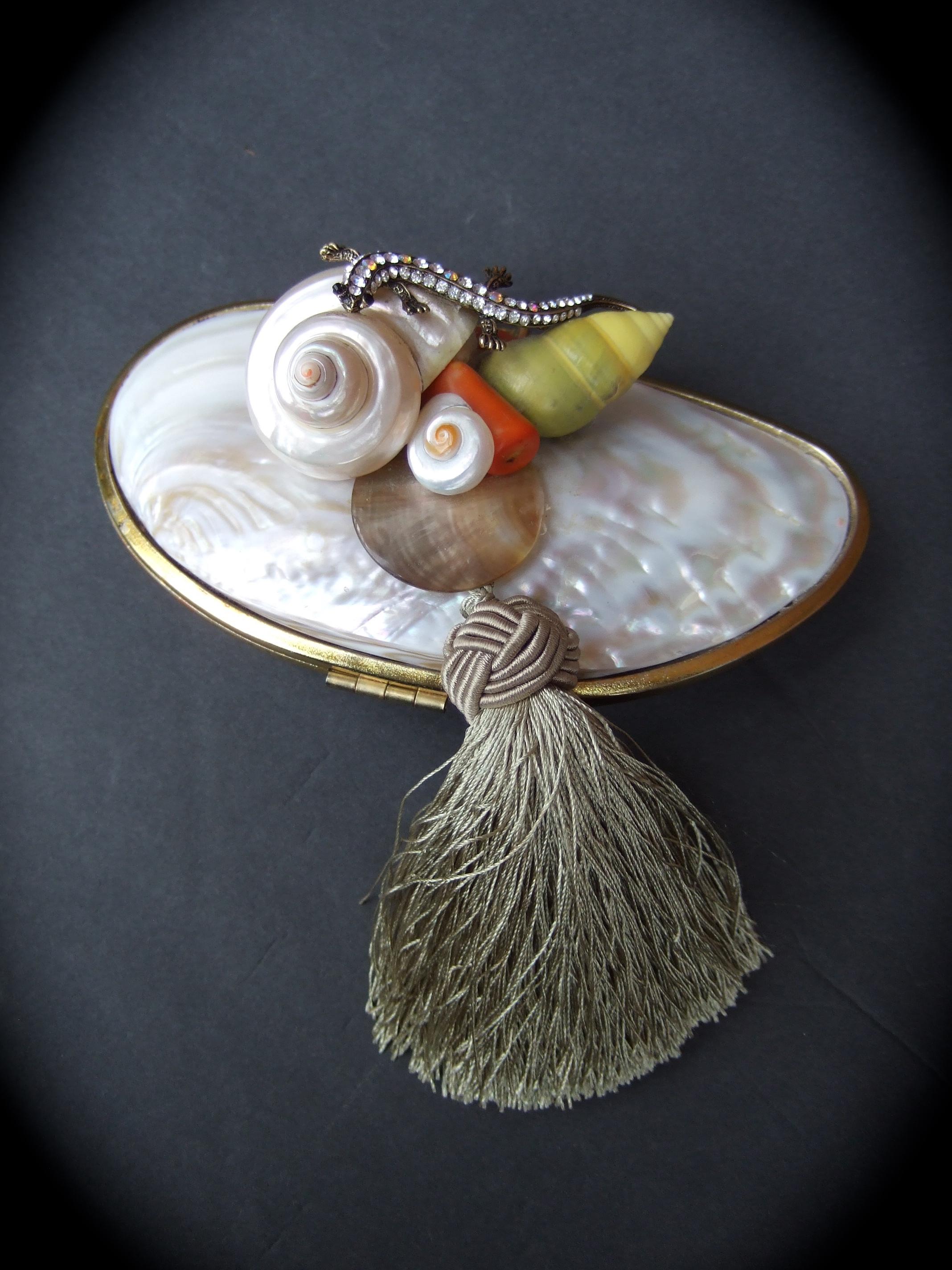 Opulent mother of pearl crystal lizard encrusted artisan clutch purse c 1970s
The exquisite artisan clutch is designed with an organic mother of pearl clam shell 
Embellished with a sinuous crystal lizard; surrounded with a collection 
of sea shells