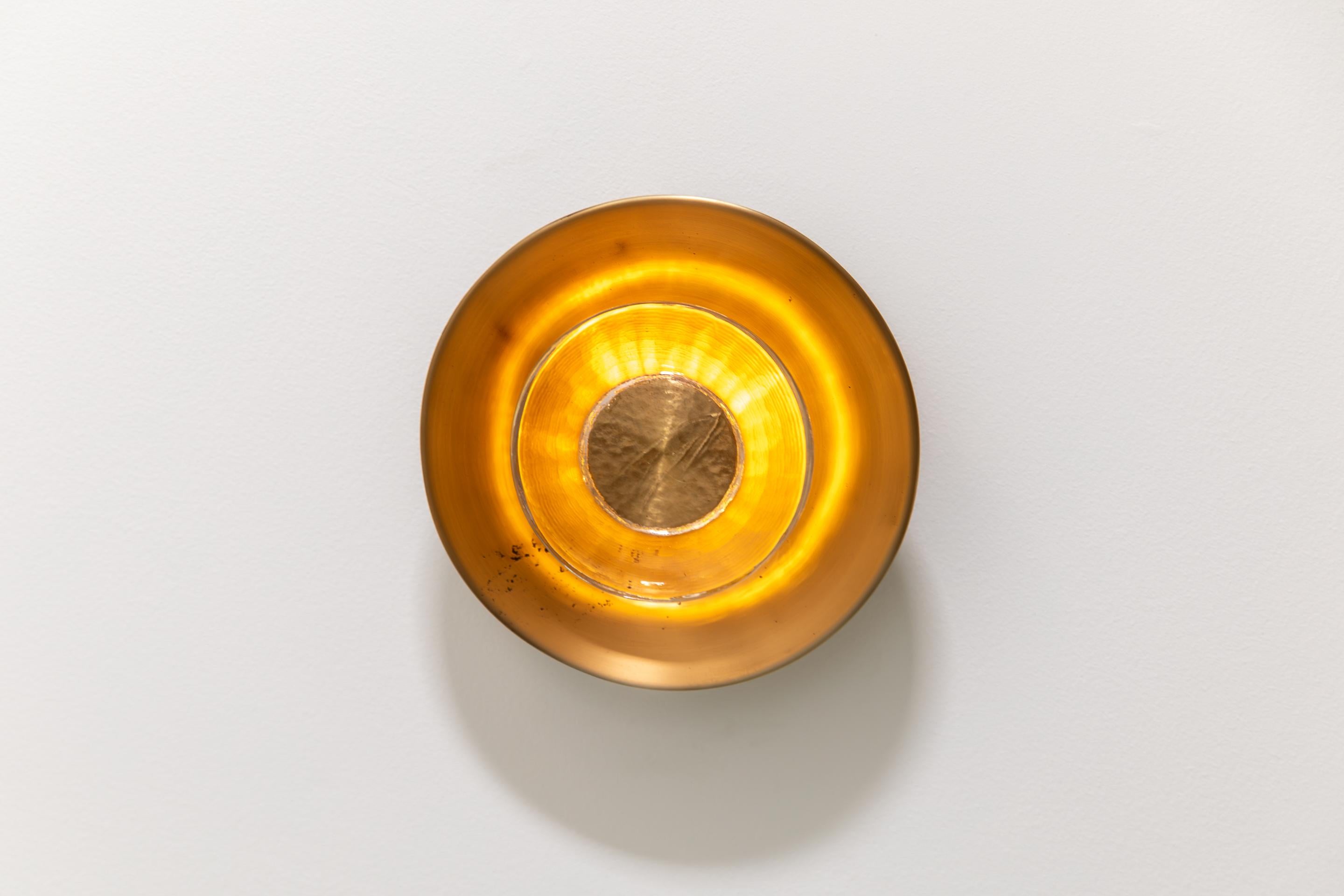 Elégante et architecturale, l'applique Ora de Brian CHAABAN apporte un sens raffiné de l'équilibre et de la matérialité à tout intérieur. Un support métallique central ancre un cylindre de verre fini à la main, émettant une douce lueur qui s'intègre