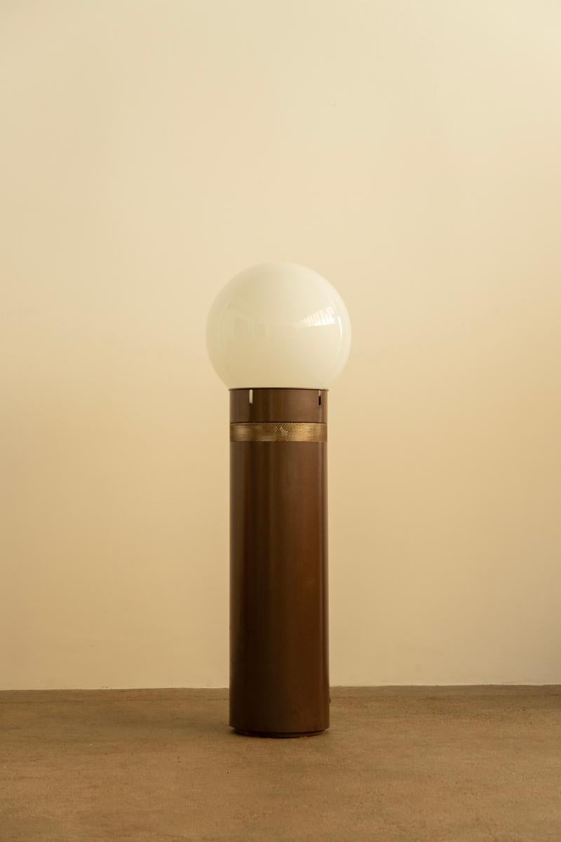 Designed in 1969 by Gae Aulenti for Artemide, the Oracolo floor lamp features a cylindrical brown lacquered metal base, a pierced stainless steel detail, and a blown glass diffuser. Aulenti, one of Italy’s most influential postwar designers, was