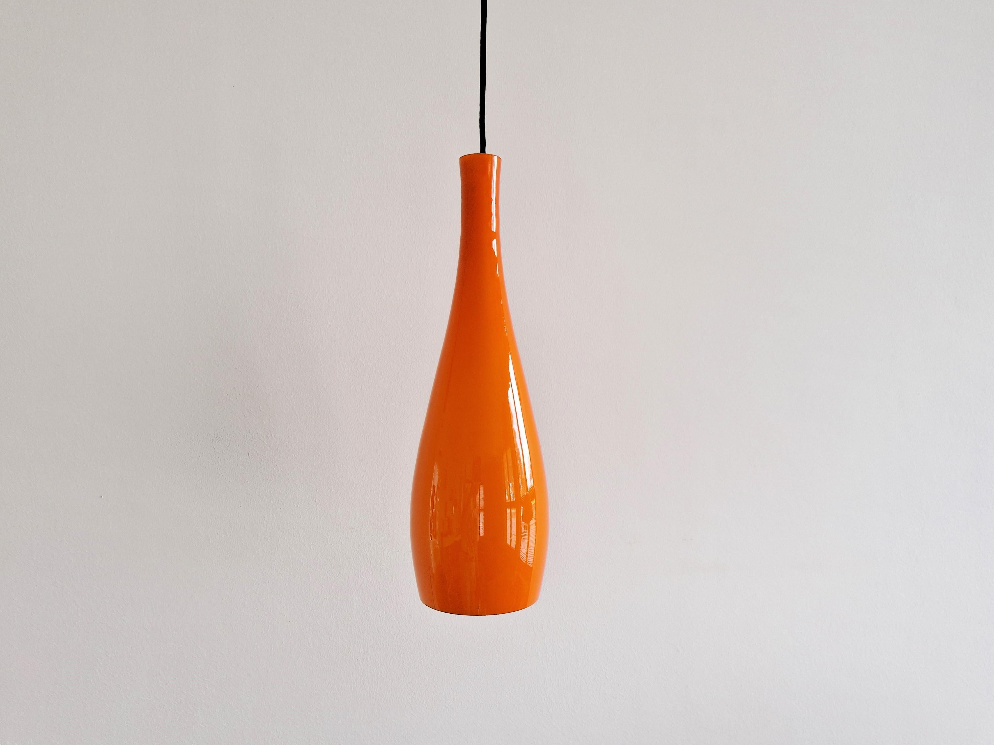 The elegant, droplet shaped pendant lamp, model 'Bang' was designed by Jacob Eiler Bang for Fog & Mørup in Denmark in the 1960's. This lamp is made of orange colored glass with a white opaline inside that spreads a beautiful warm and soft light. It