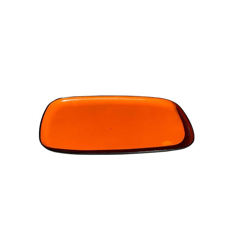 A bright orange and black lacquerware tray by Davar. This rectangular tray has smooth corners and is orange on top, and black on the bottom. Davar is known for its pieces that are impervious to alcohol, and stains. 

How we would style it:
This