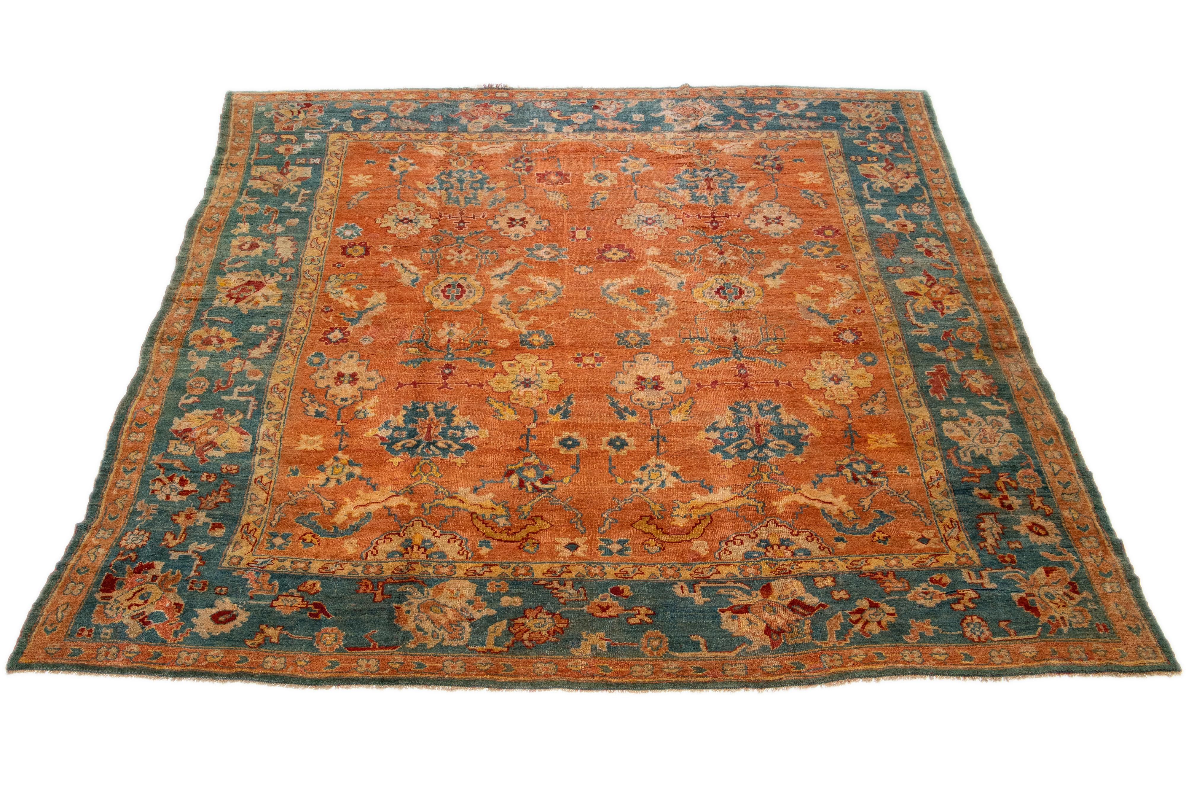 Ce tapis turc Oushak est vraiment unique en son genre. Il a été noué à la main de manière experte avec de la laine de première qualité et arbore un champ orange époustouflant. Le tapis est encadré d'une bordure bleue audacieuse et orné d'un vibrant