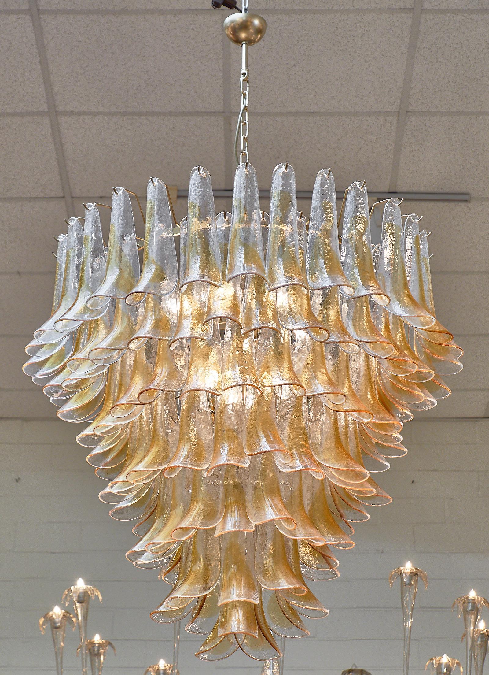 Murano orange and clear glass “selle” chandelier. This stunning work of art from the artisans in Murano, Italy created this piece out of clear glass with an organic stripe of orange-amber glass hand-blown through each piece. The fixture requires 9