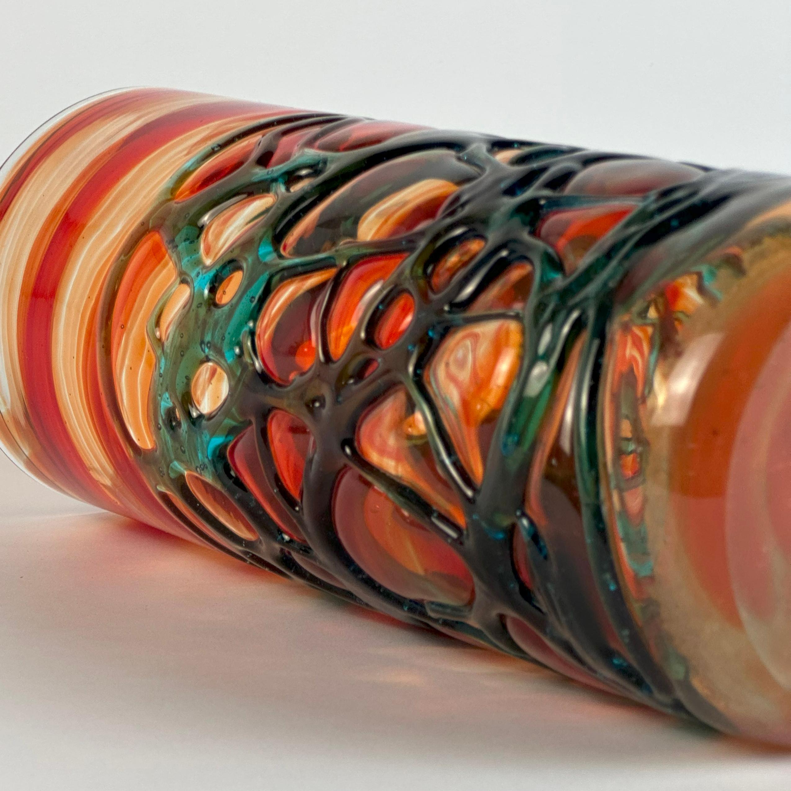 Exemple évocateur du verre d'art des années 1980, ce vase cylindrique a été produit par Mdina Glass à Malte sous la Direction de Michael Harris, une figure centrale dans le développement du design du verre britannique et méditerranéen. Datée du
