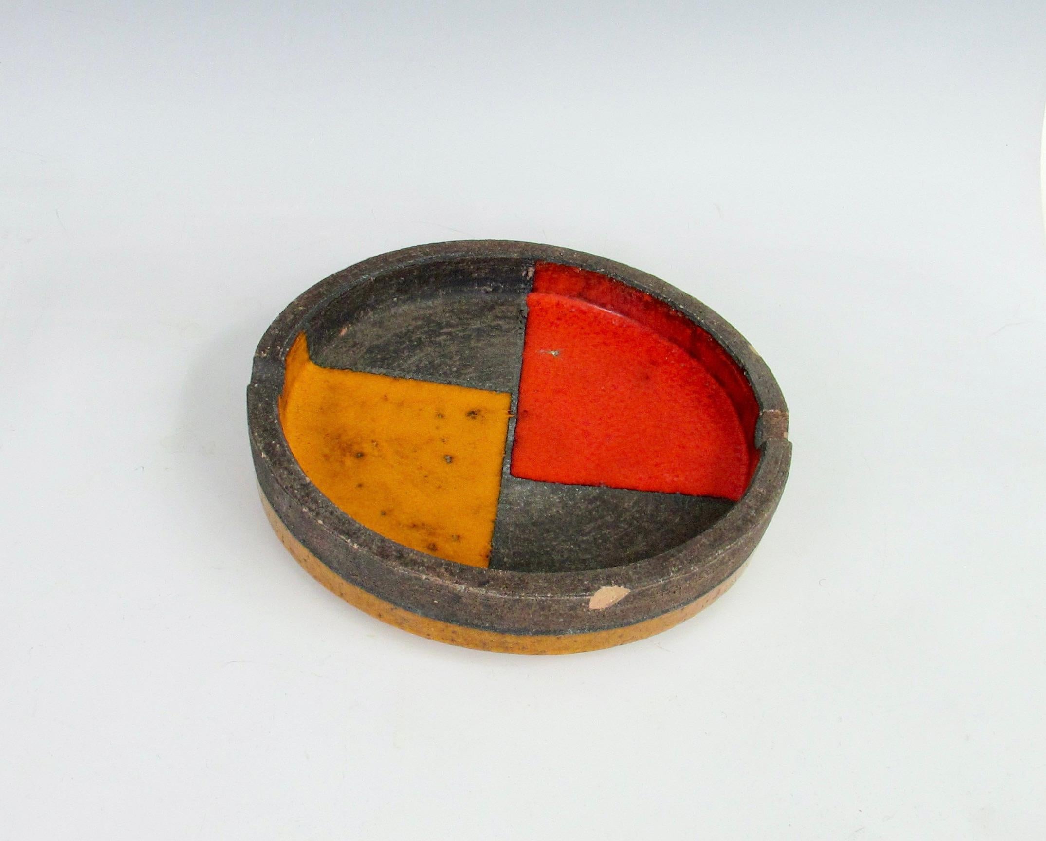 Chunky round ashtray signed Italy . Glazed geometric decoration of orange and red over raw terra cotta base . There are two edge chips and one chip in the red glaze . 