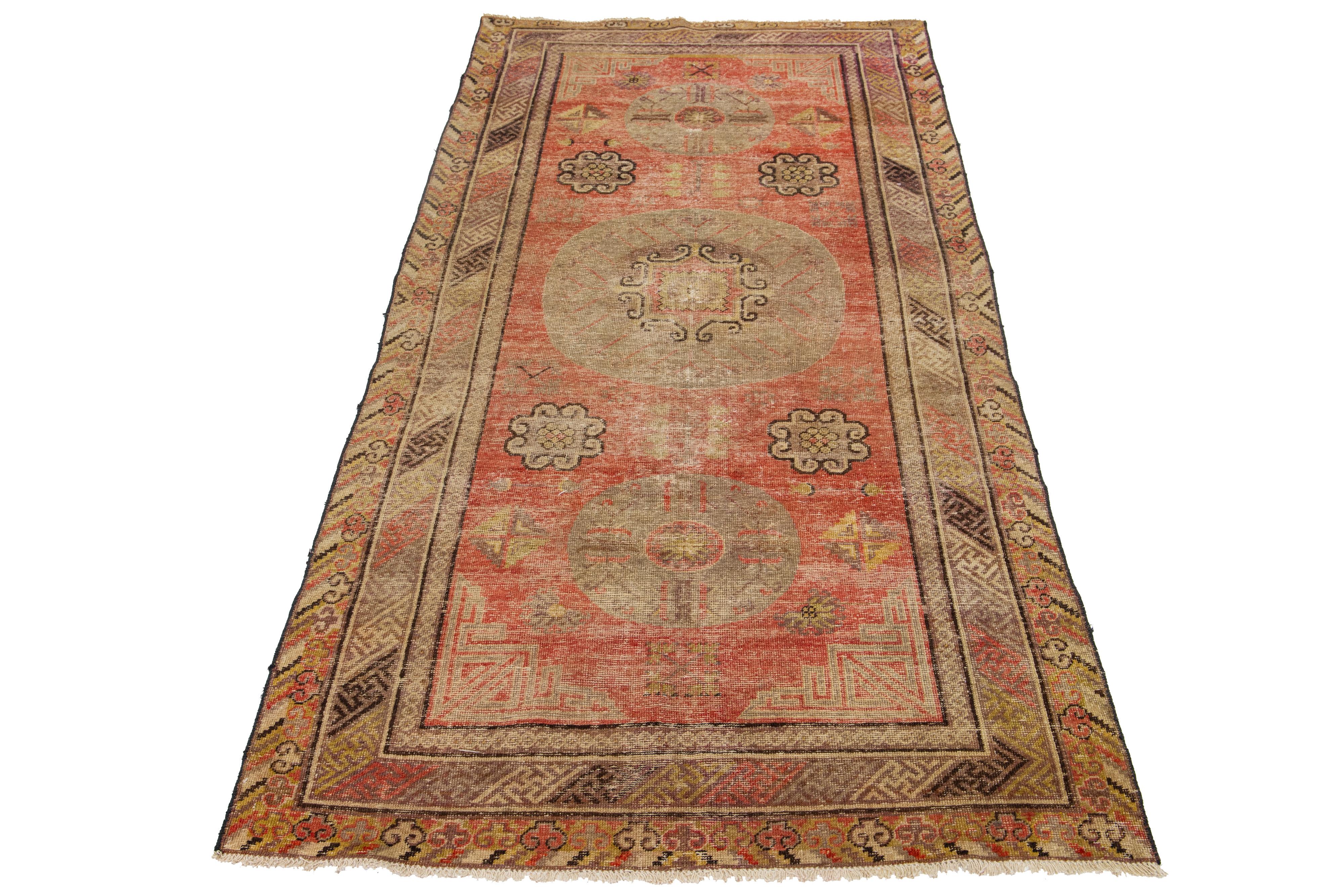 Beautiful Antique Khotan hand-knotted wool rug with an orange color field. This Khotan has multicolor accents in a gorgeous all-over medallion floral motif.

This runner measures 4'4
