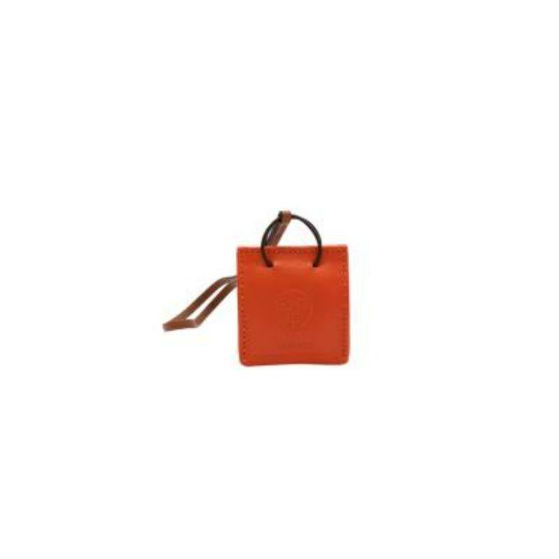 Hermes Orange Bag Charm 
 
 - Milo Calfskin leather bag charm iteration of the iconic bright orange Hermes gift bag hanging from a tan leather strap 
 - Central 