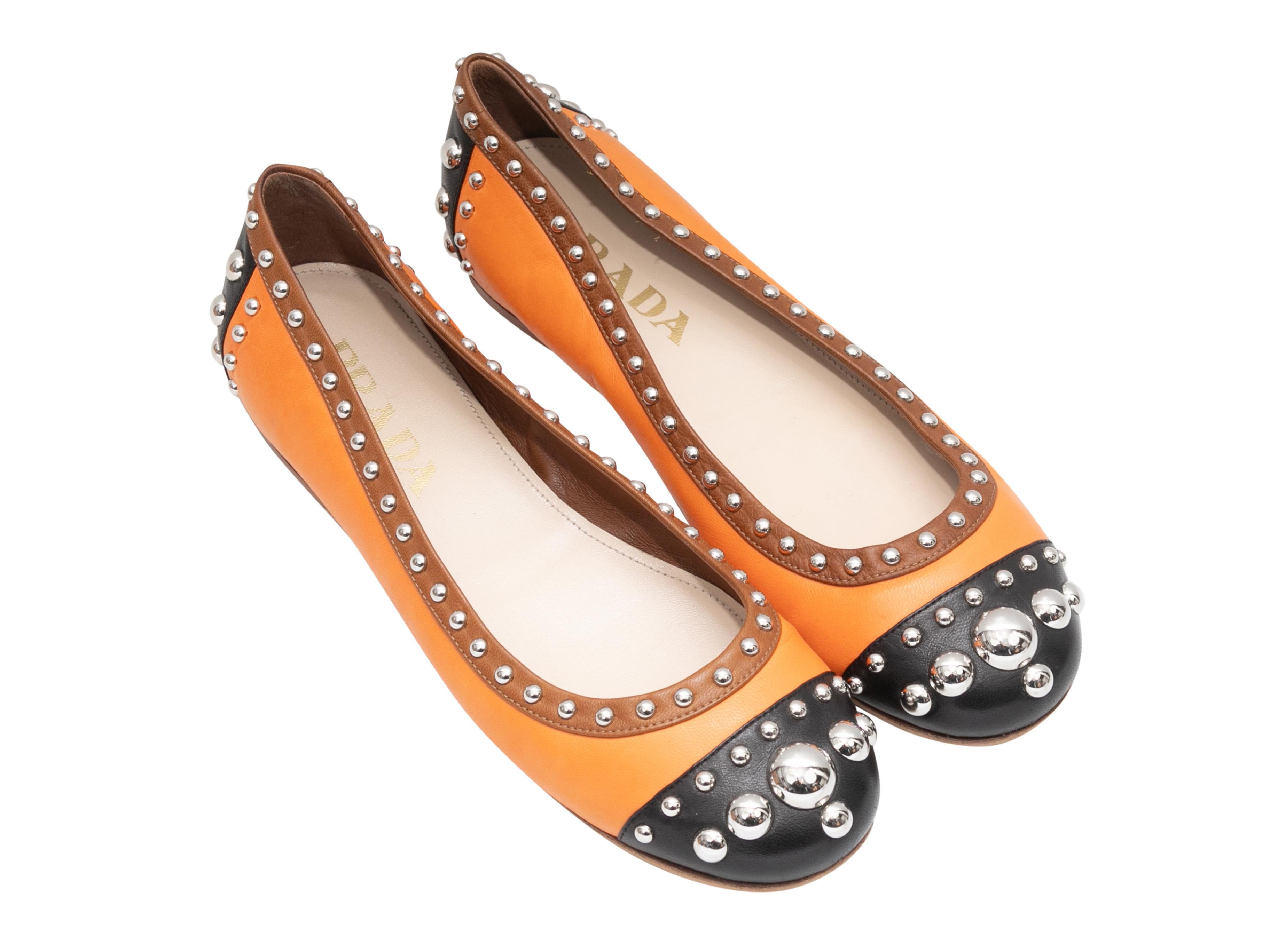 Orange and black cap-toe leather ballet flats by Prada. Silver-tone studs throughout. 0.25