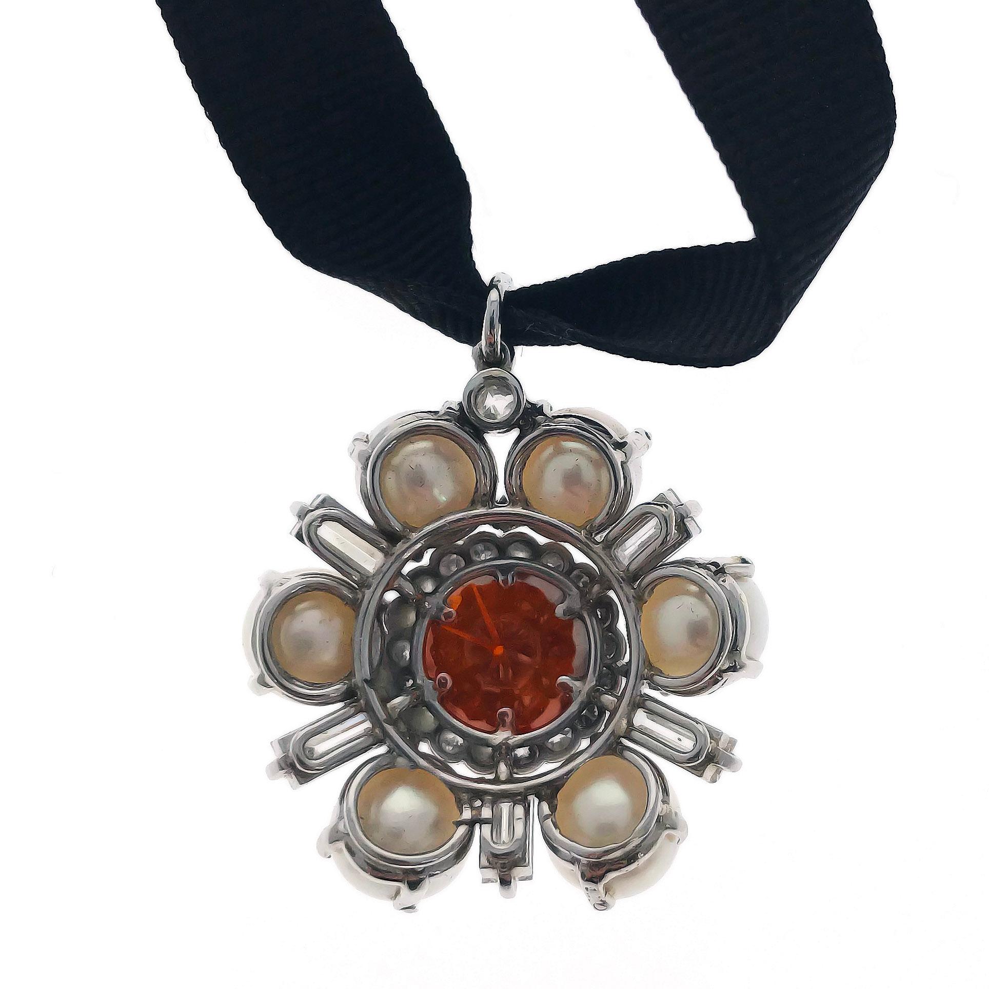 This unique pendant with stylized flower motif, centers upon an HPHT treated orange brown diamond of 6.10 carats. It is encircled with a row of brilliant-cut diamonds, and bordered by alternating cultured pearls and baguette-cut diamonds. The