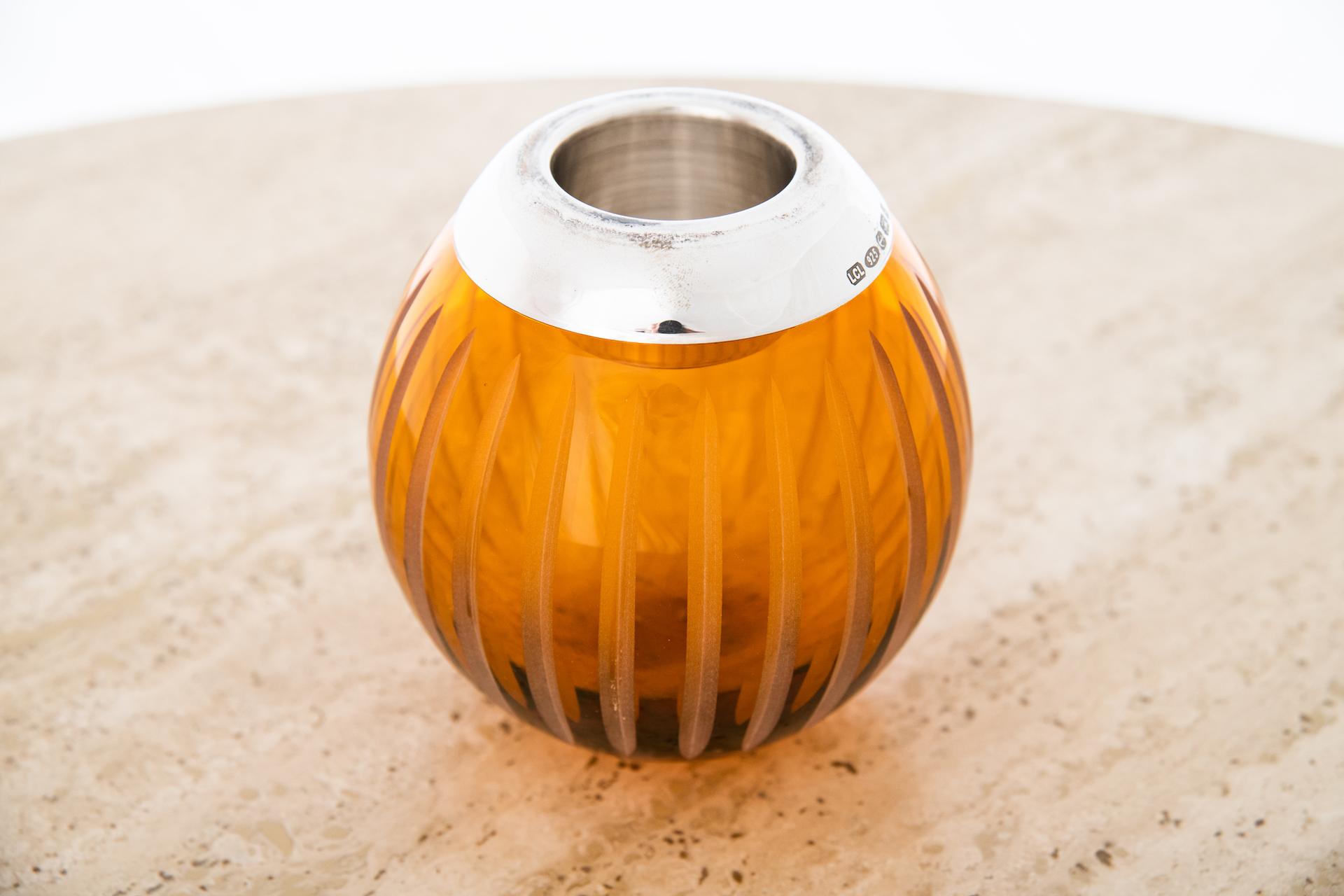 A medium mouth-blown crystal match strike in orange. The sterling silver rim is marked with the British silver assay marks for Birmingham, England. The repeating decorative cut and etched “splits” function as the striking surface for matches.
