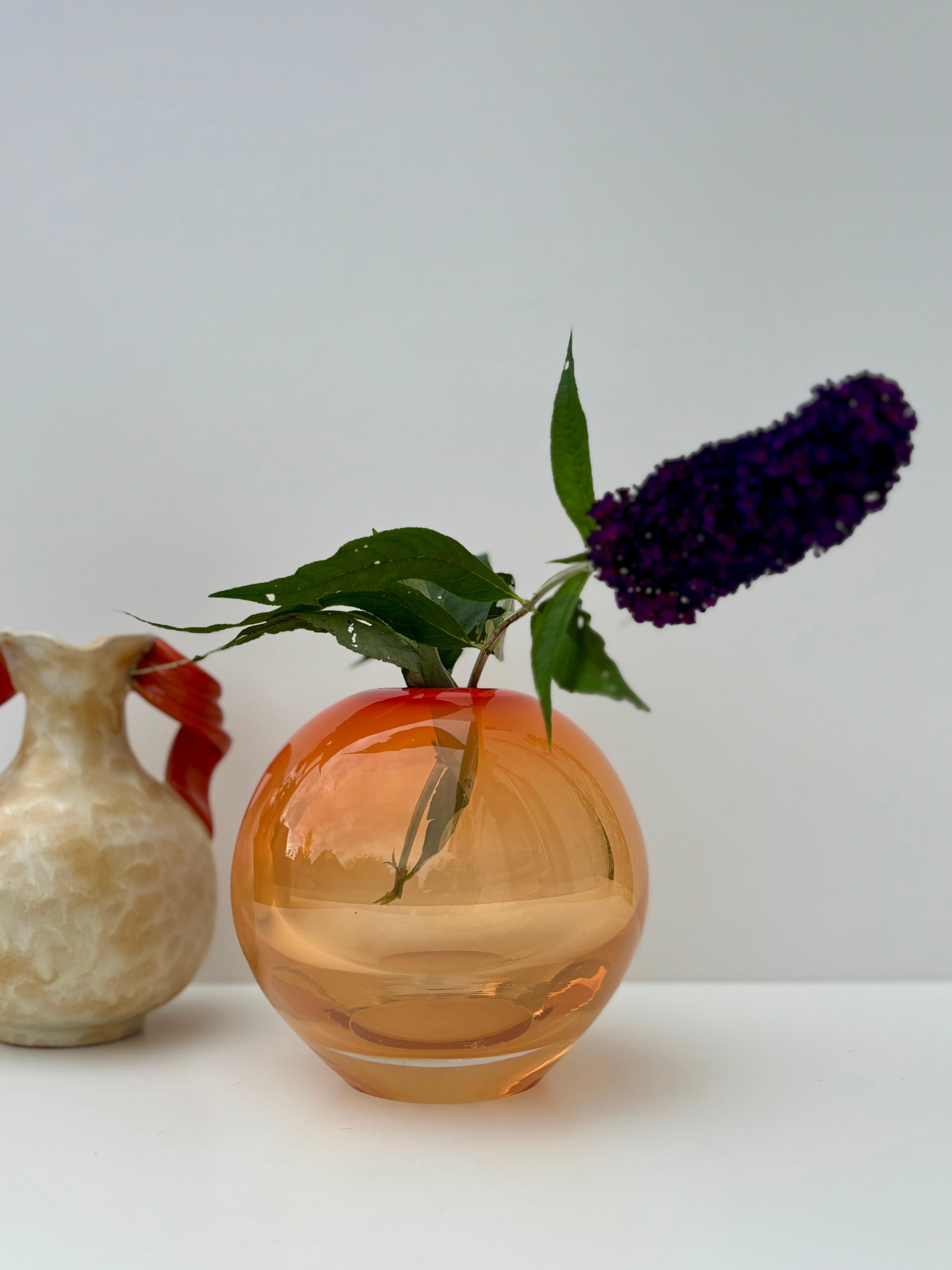 Unico vaso danese in vetro artistico della metà del secolo scorso in vetro arancione massiccio e molto pesante racchiuso in vetro trasparente in stile Sommerso. Forma rotonda con parte superiore arancione e base trasparente. Straordinaria bocca