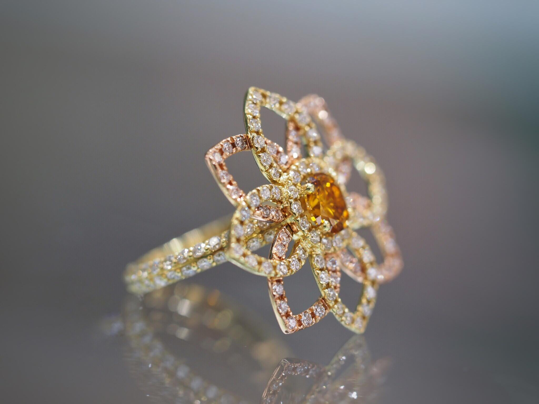 This custom made flower ring includes a 0.72ct orange oval diamond center set in a stunning nature inspired flower design ring. There are 1.56ctw of round brilliant cut diamonds accented on the leaves and down the sides of the ring. It is 18k rose