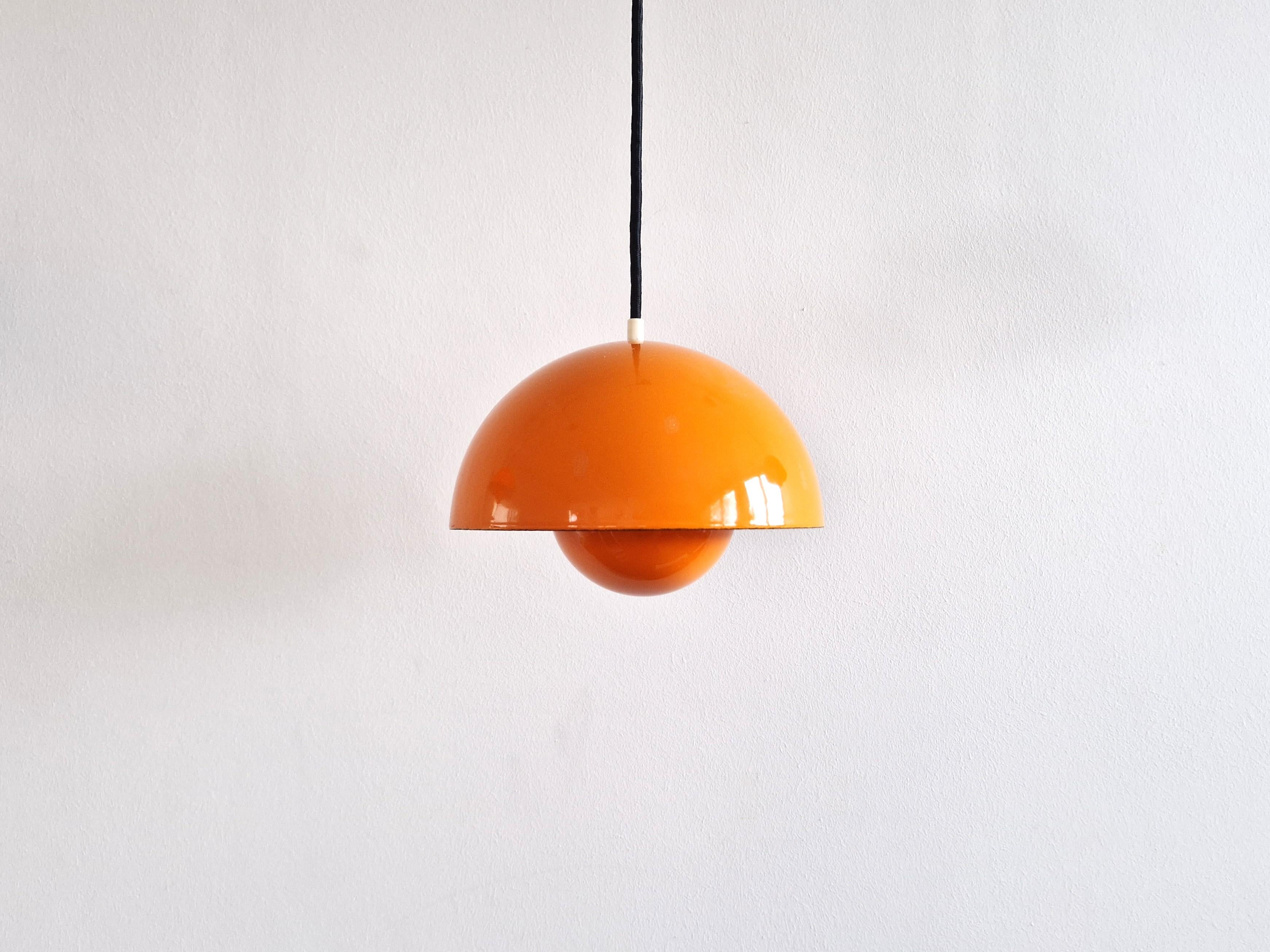 La lampe suspendue Flowerpot a été conçue par Verner Panton pour Louis Poulsen en 1968. Un beau classique du design qui est toujours en production. Cette lampe est une version précoce et a une finition émaillée orange à l'extérieur et blanche à