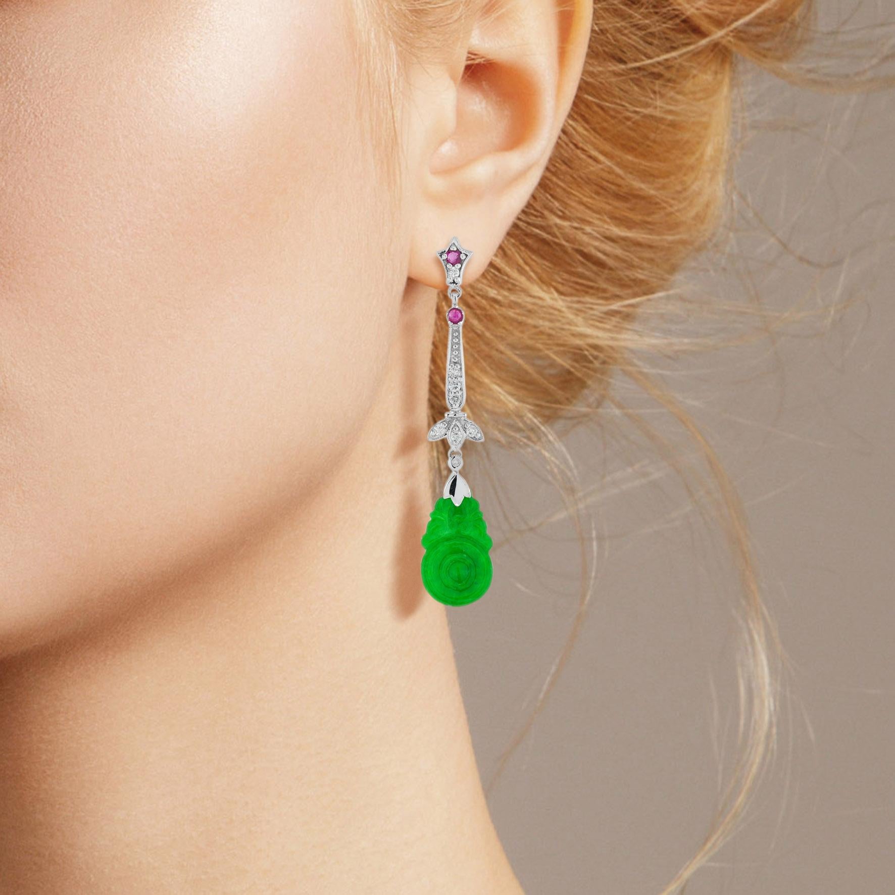 The natural jade in these lovely earrings has some very special shape. Both pieces have a strong green color and well orange fruit carvings. The jade is suspended in a 9k white gold setting with diamond leaf and round rubies on the top. The earrings