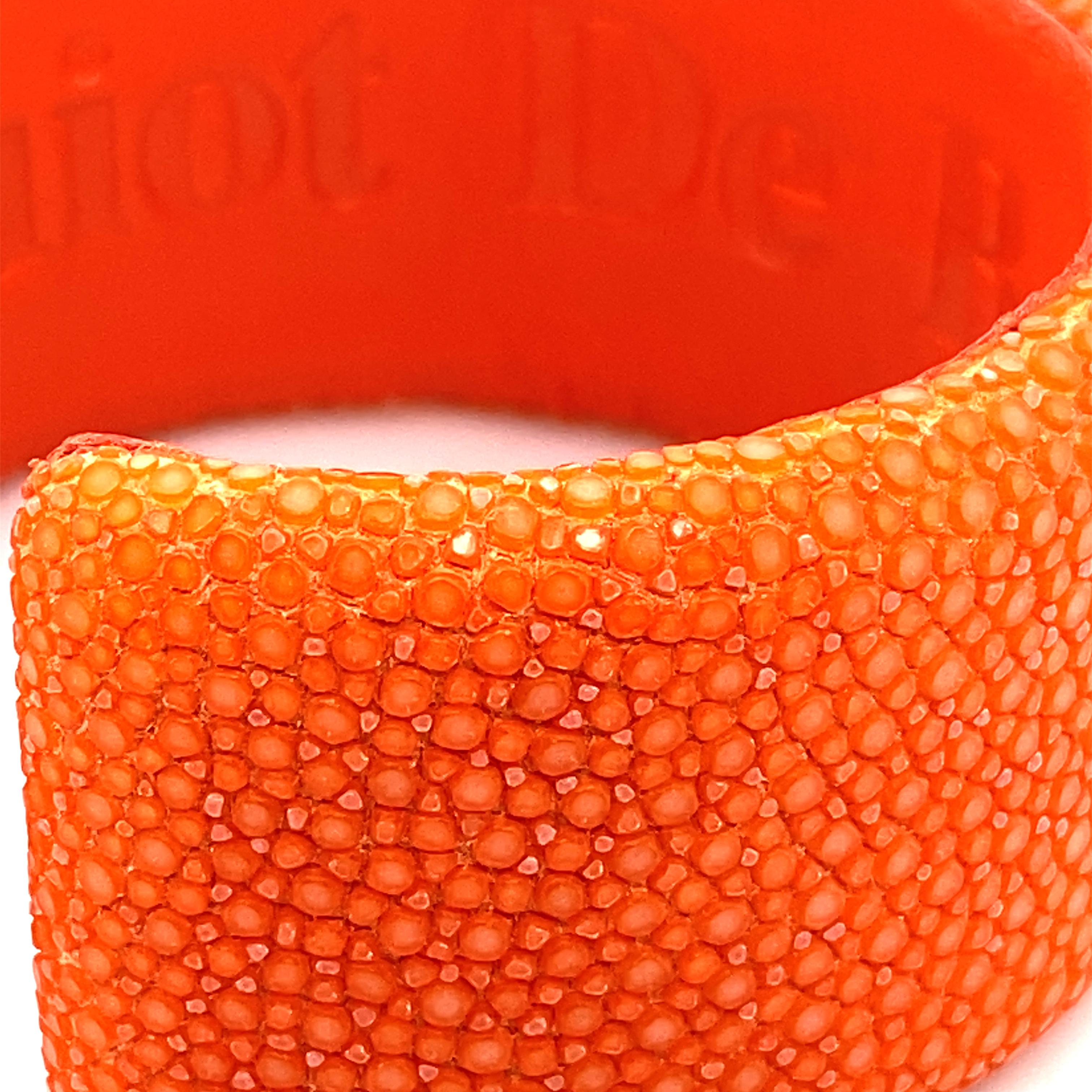 The orange stingray cuff bracelet is a true masterpiece of craftsmanship, designed for lovers of refined and unique jewellery. Made from high-quality stingray, this accessory has a distinct texture and a vibrant orange hue that is sure to catch the