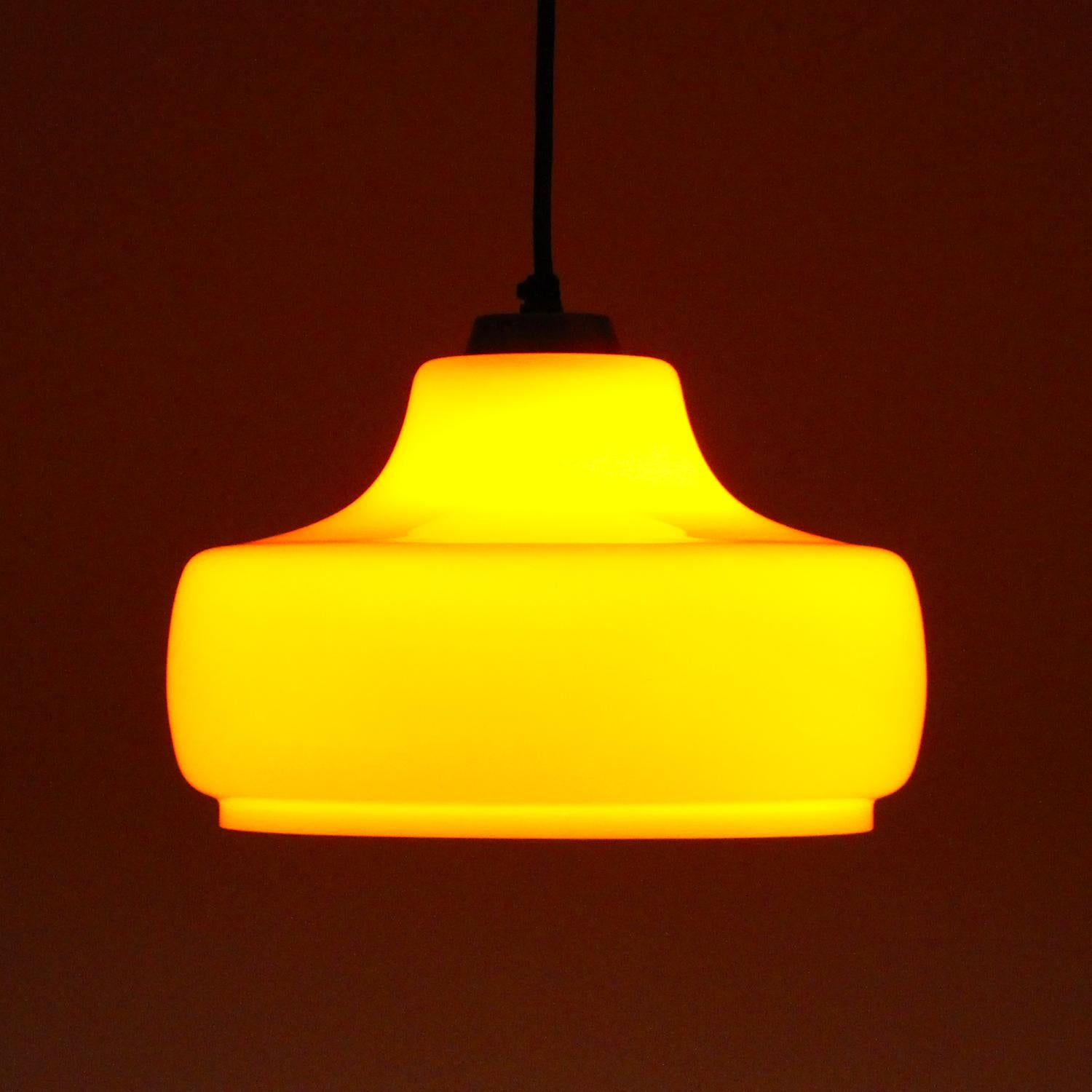 Orange glass hanging lamp by Holmegaard (presumed) in the 1970s - Danish vintage blown glass pendant in excellent vintage condition.

A blown double-layered glass pendant with a charming organic shape and a flat brass top to secure both the bulb