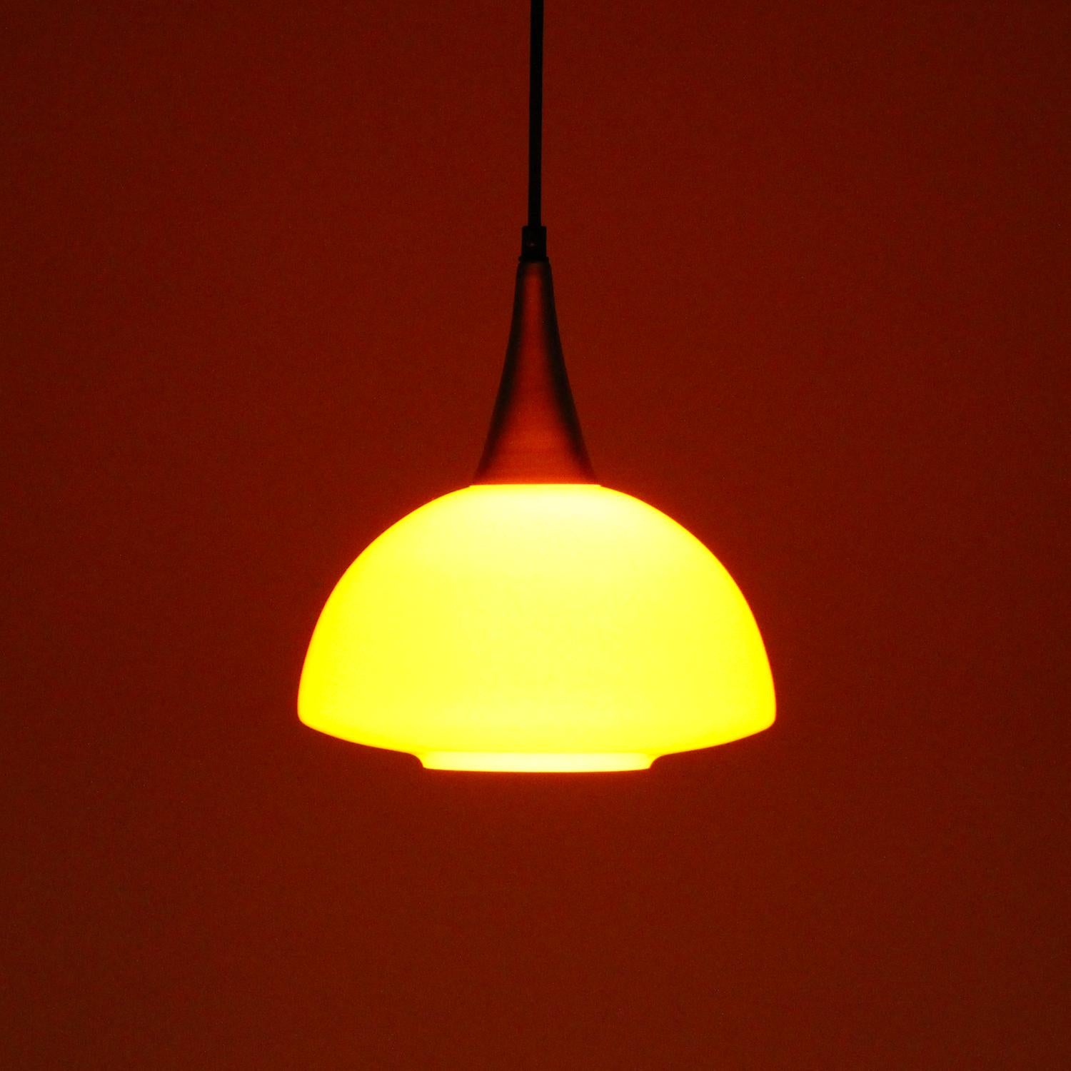 Orange glass pendant by Holmegaard (presumed) in the 1970s - Scandinavian Modern blown glass hanging light with brass lacquered top, in very good vintage condition.

This charming blown glass pendant is comprised of a two-layer blown glass shade,
