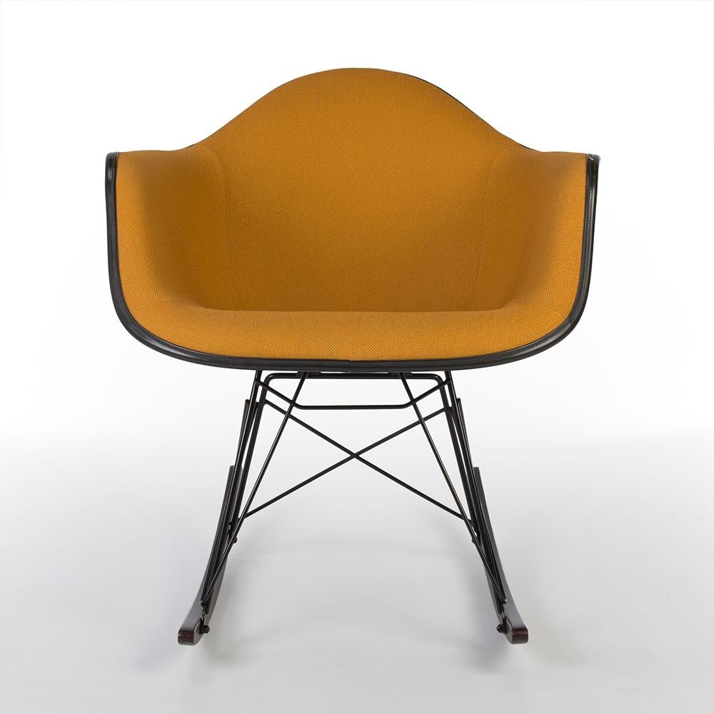 A wonderful example of a used, newer, orange, original, upholstered black Eames arm shell chair on a brand new RAR base for Herman Miller is in good condition. The new RAR walnut wood base differs from the picture shown above, it is of a more