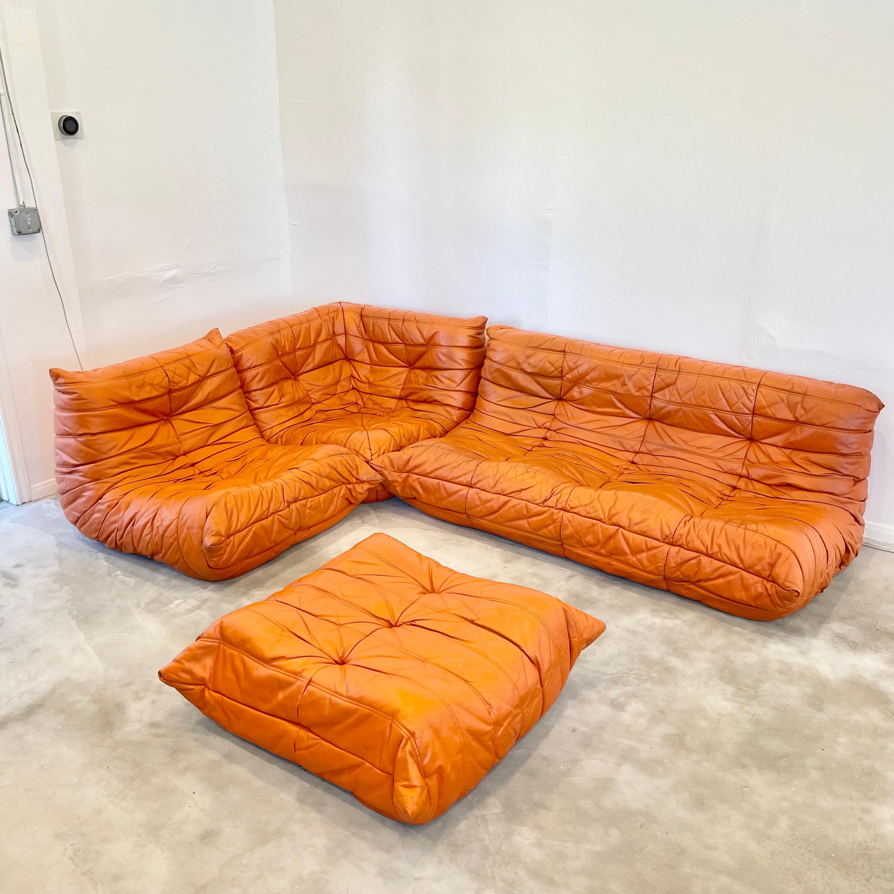 Classic French Togo set by Michel Ducaroy for luxury brand Ligne Roset. Originally designed in the 1970s the iconic togo sofa is now a design classic. This set comes in its original orange leather.

Timeless comfort and style make this four piece