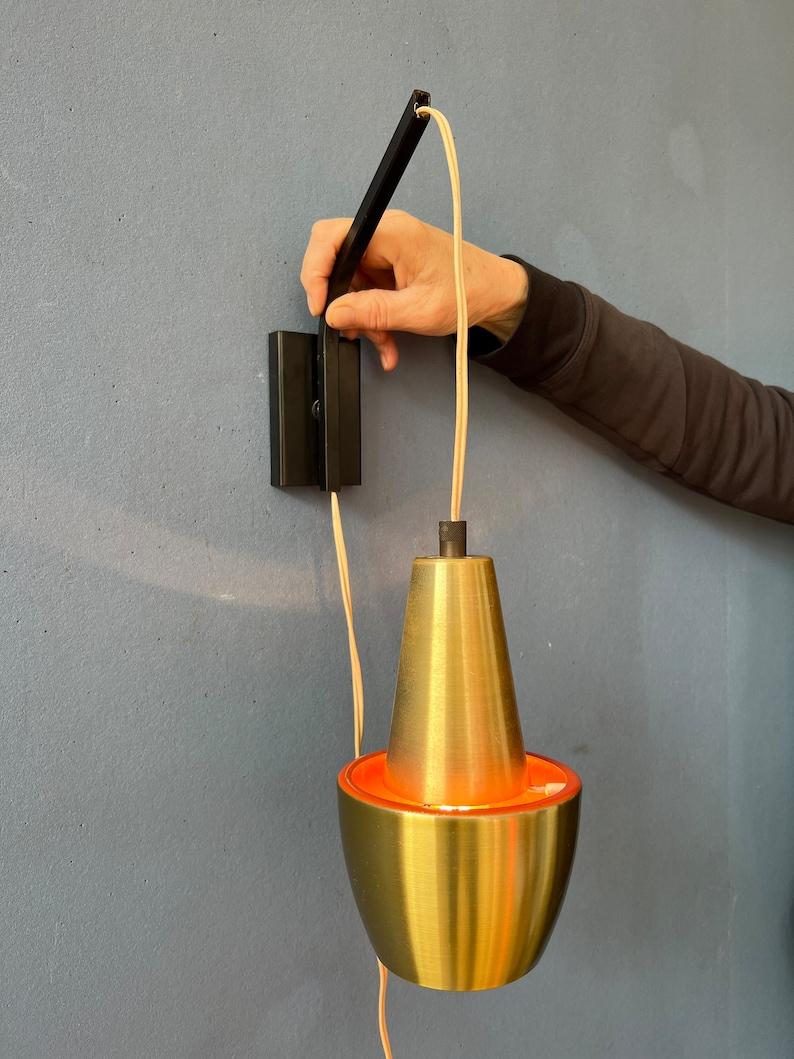 Seltene dänische Wandlampe mit orangefarbenem vulkanischem Licht aus der Mitte des Weltraumzeitalters. Die Höhe des hängenden Schirms kann einfach durch das Ziehen des Drahtes durch die Wandhalterung eingestellt werden. Die Wandhalterung ist aus