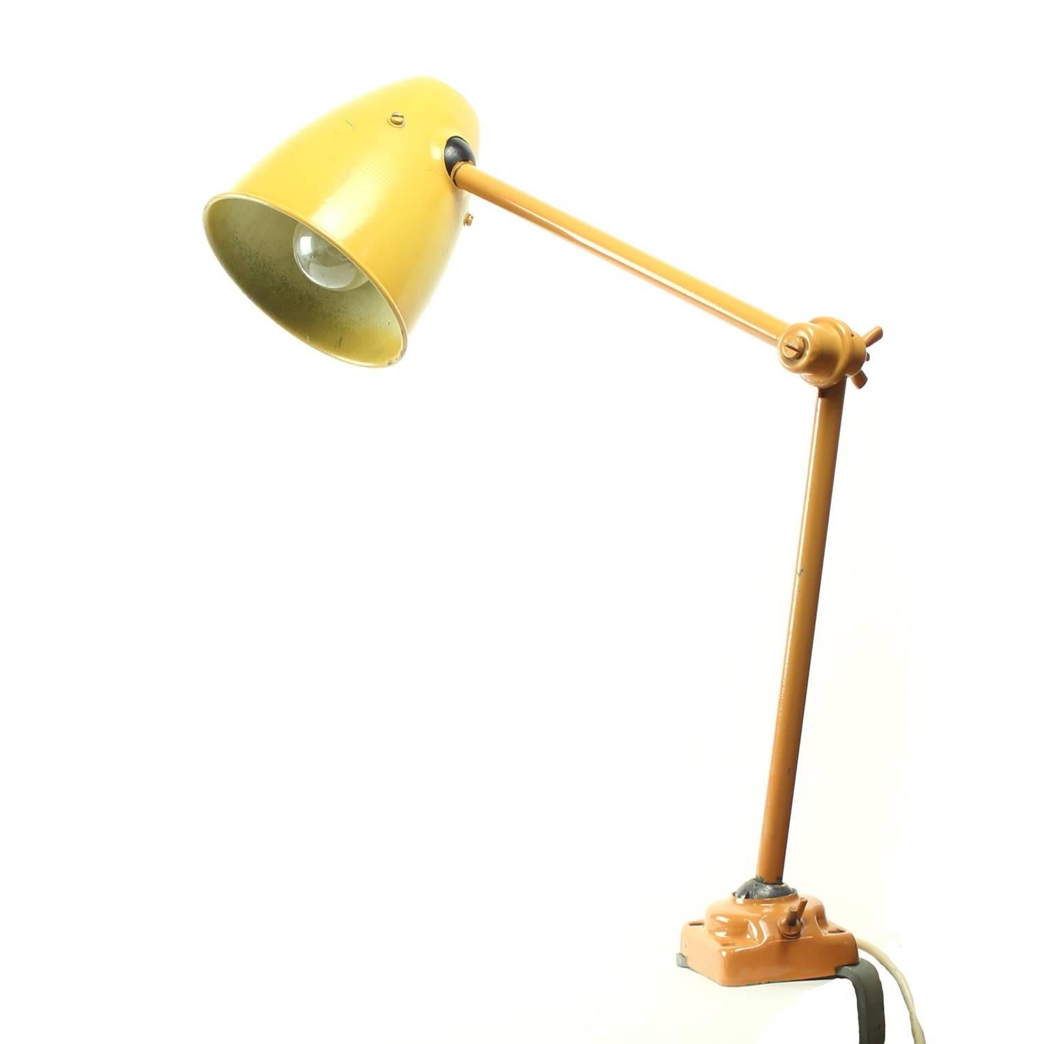 Simple, strong and very industrial. In its original orange color, this office lamp will make a statement on any working desk. The metal construction is in more orange color, the shield is also made of metal and is more yellowish. The lamp is made
