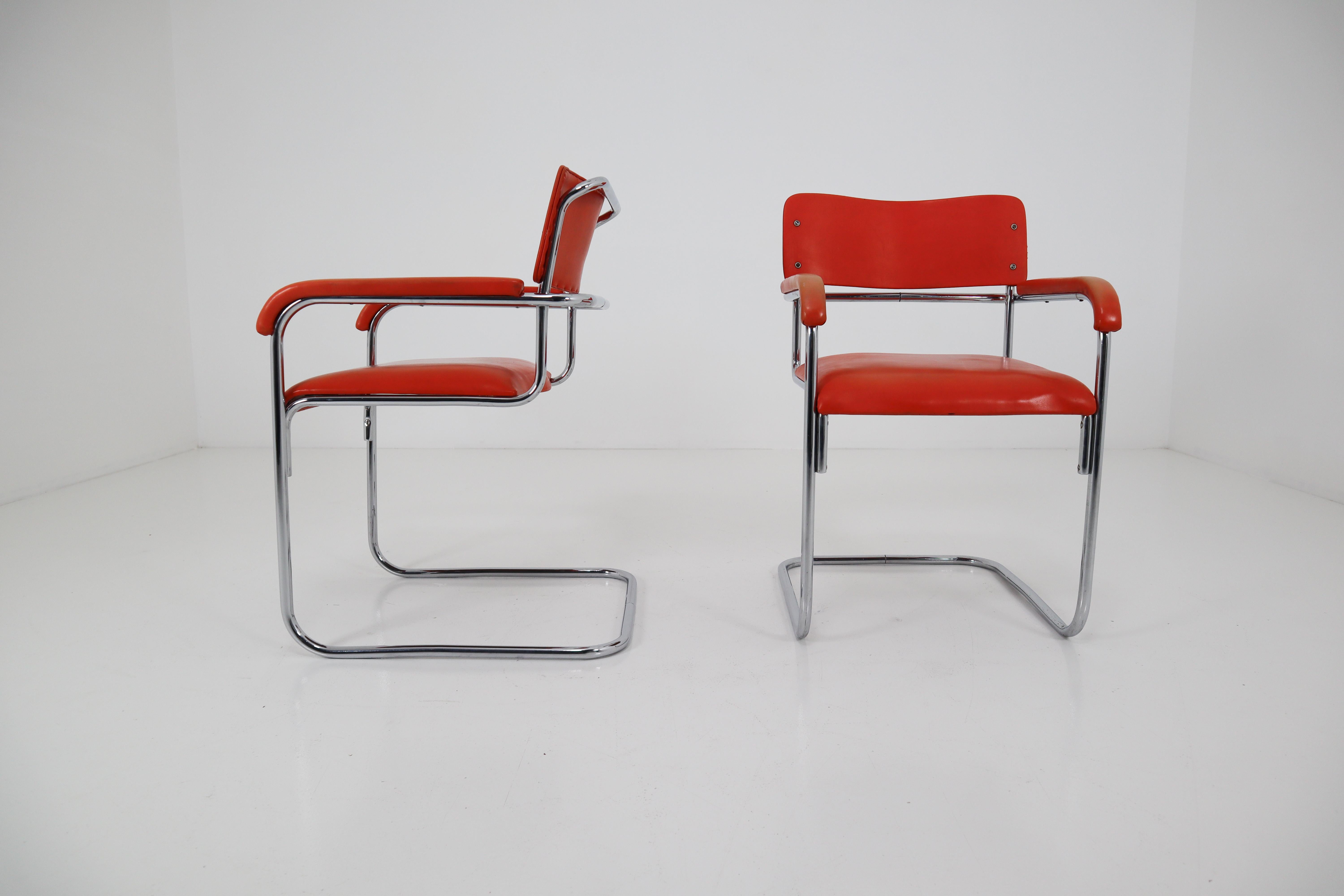 Iconic and distinctive Bauhaus design cantilevered chromed steel tubular armchair featuring original orange color back, and arm rests. This modern armchair can also be used as an accent lounge chair or stylish desk chair. In the style of Thonet and