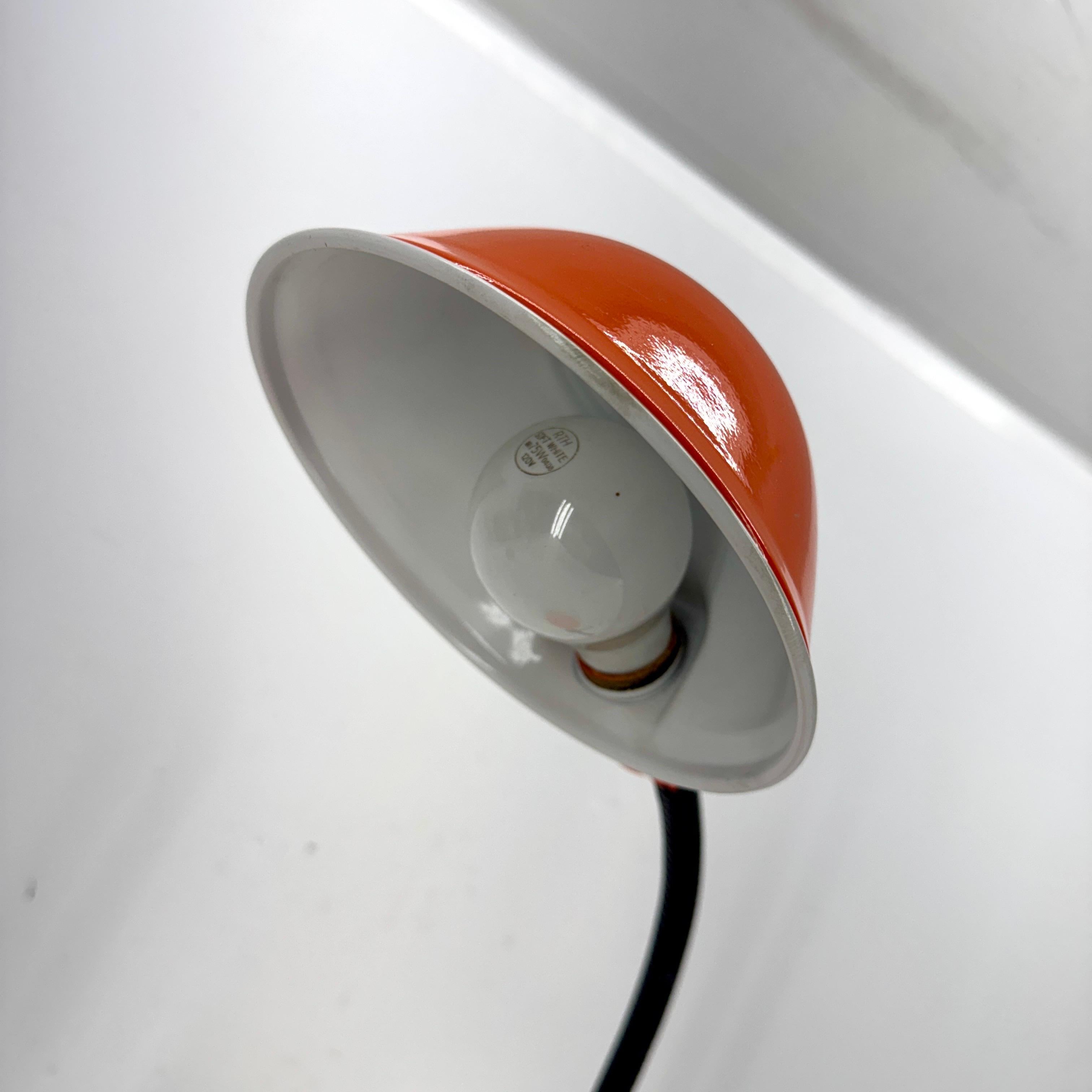 De diseño clásico de mediados de siglo, esta lámpara metálica de sobremesa o escritorio brilla en un acabado naranja con recubrimiento en polvo. Su silueta atemporal incorpora un brazo articulado y una pantalla de cúpula para dirigir la luz con
