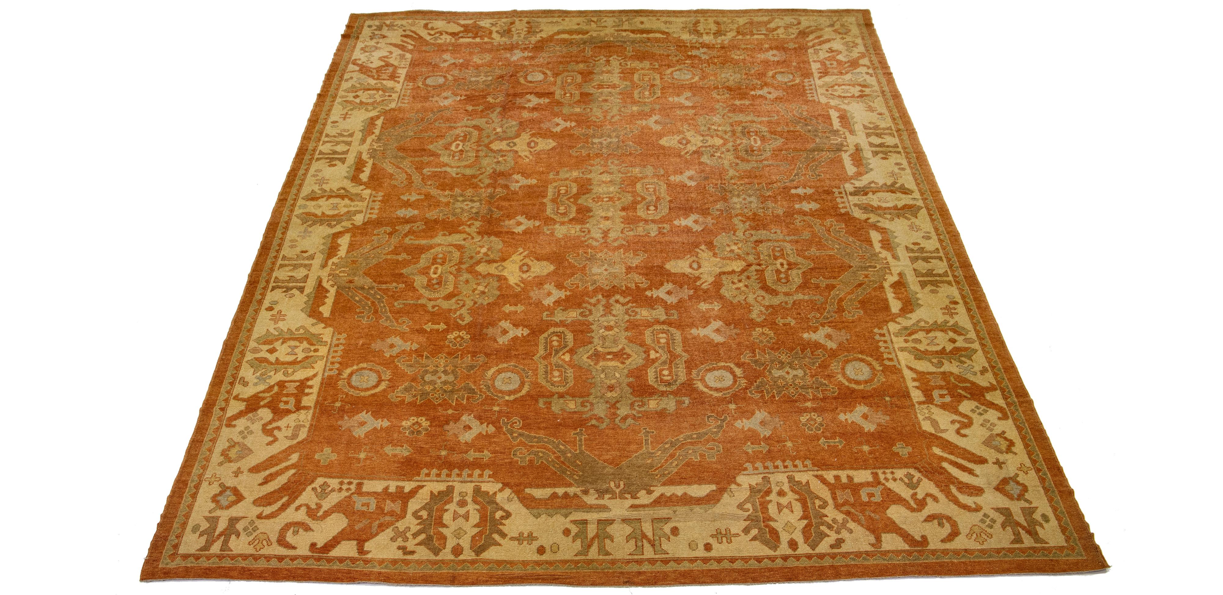 This is a modern, hand-knotted rug featuring a floral design. The primary color is orange-rust, and beige borders surround it.

This rug measures 13'10