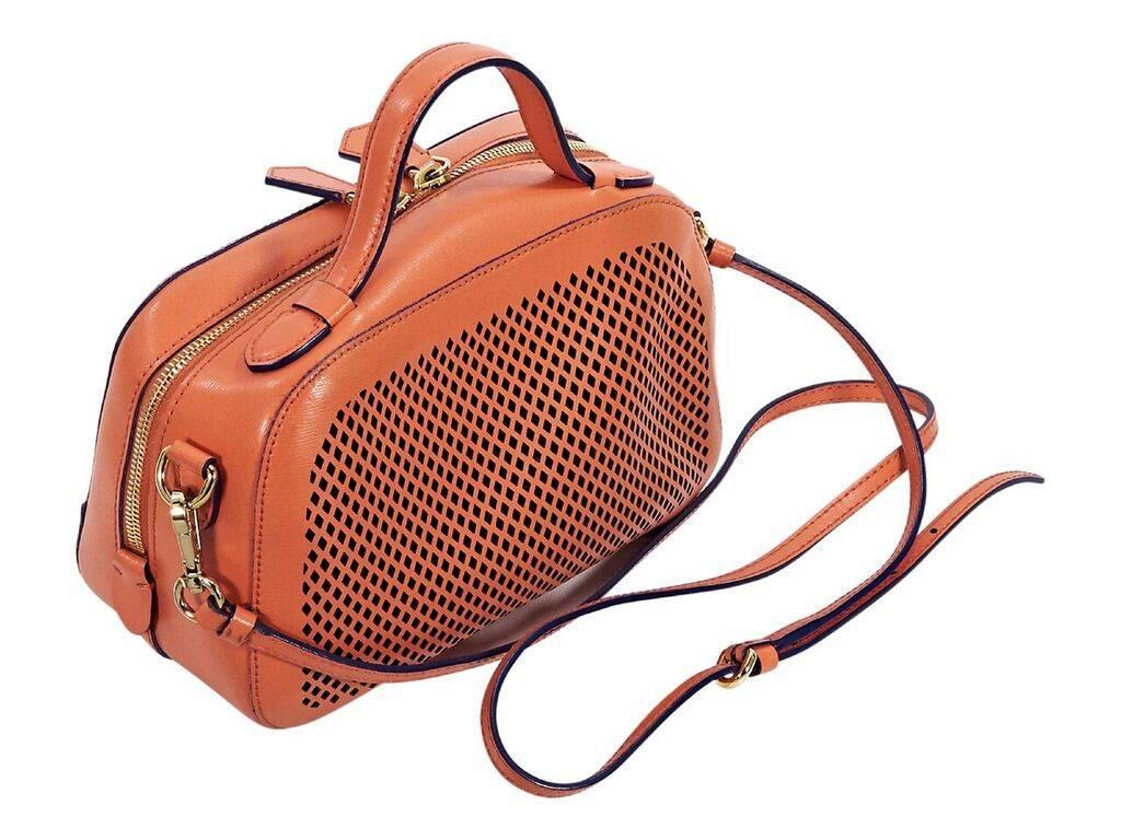 Product details:  Orange perforated crossbody bag by Moschino.  Accented wth tonal logo detail.  Top carry handle.  Detachable, adjustable crossbody strap.  Top zip closure.  Lined interior.  Protective metal feet.  Goldtone hardware.  9