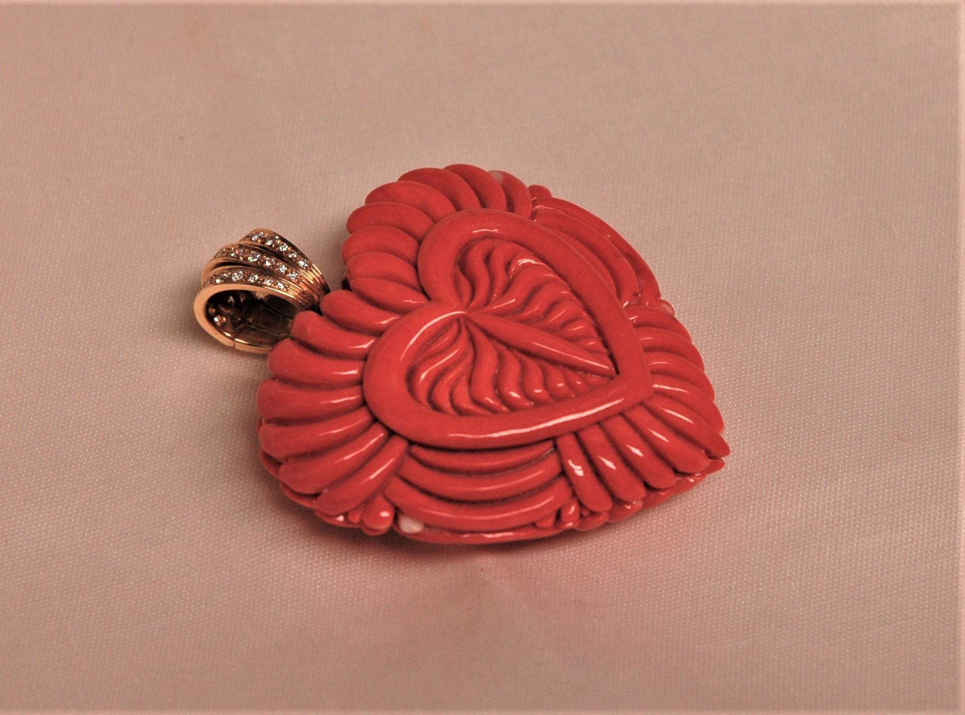 Spectacular natural coral pendant in the shape of a big heart. It has been hand-engraved on both sides and mounted in yellow gold 18 kt. with diamonds, brilliant cut, 0.60 ct. The gold counter-link can be opened. This pendant can be considered a